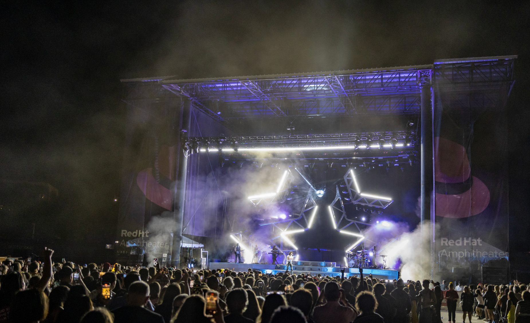 A concert stage with blue and purple star-shaped lights and an audience.