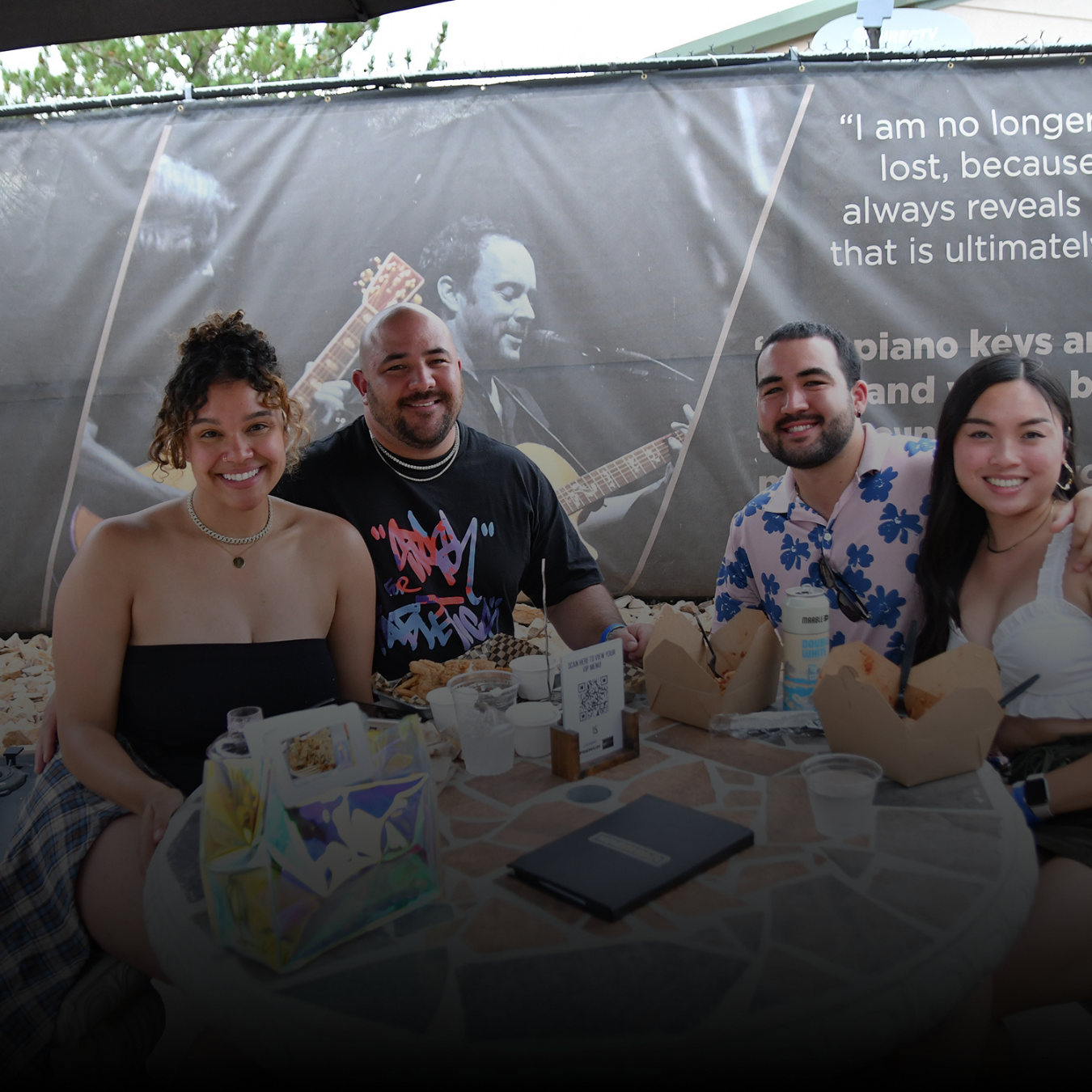 four people smiling in front of a sign 