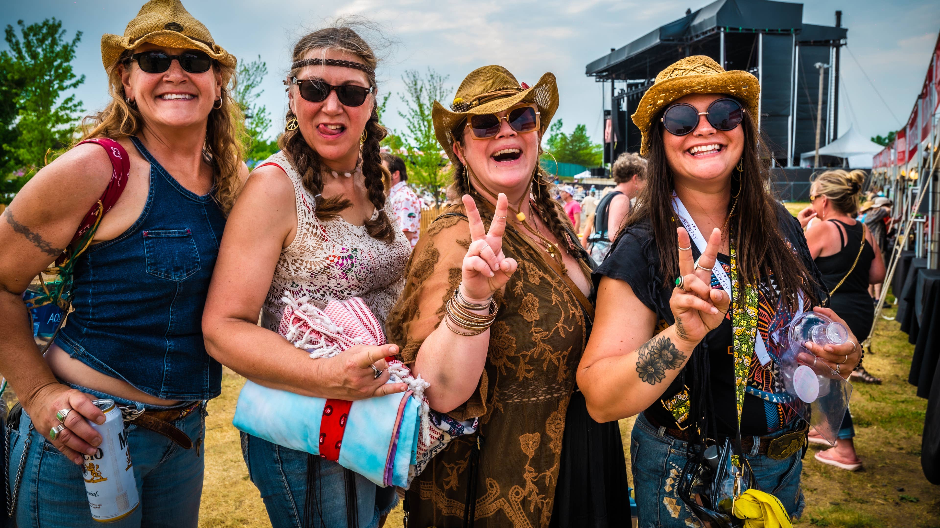 Four people pose for the camera at a concert. Two of them are giving peace signs.