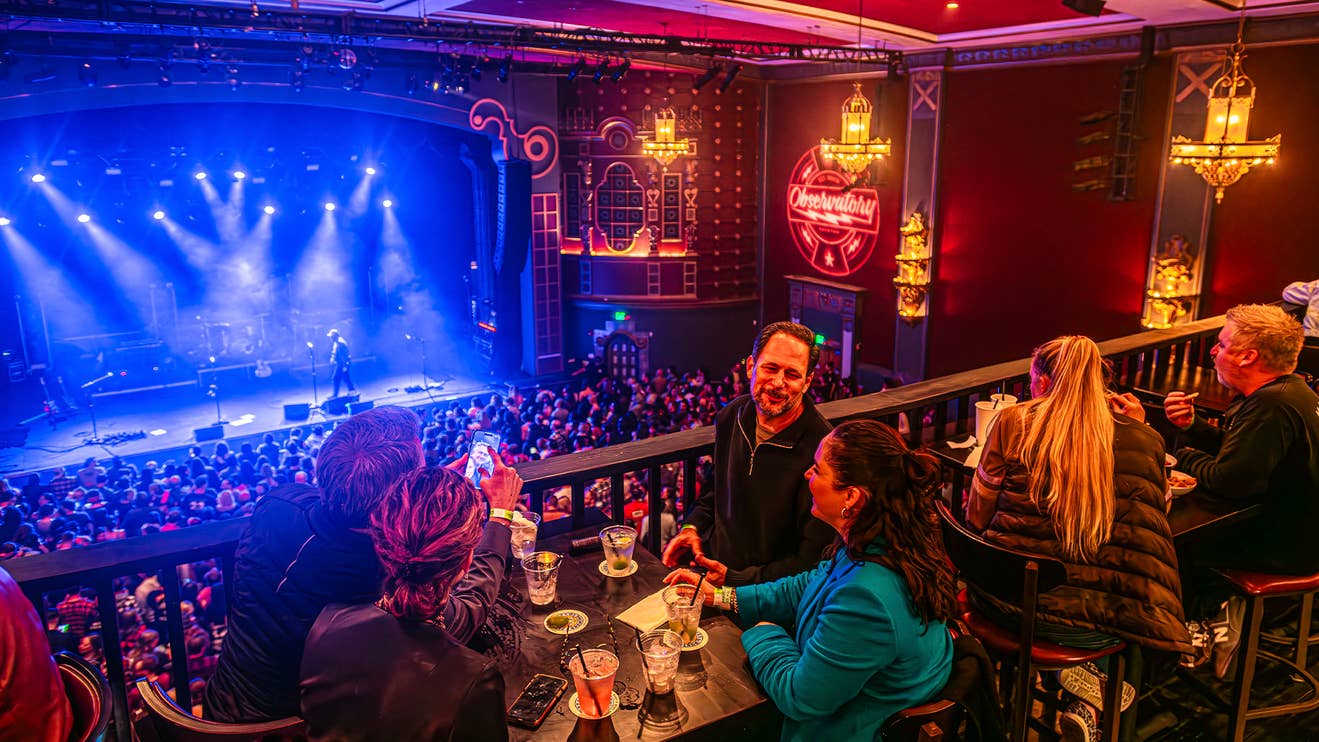 Attendees standing and talking amongst each other on the balcony of a venue