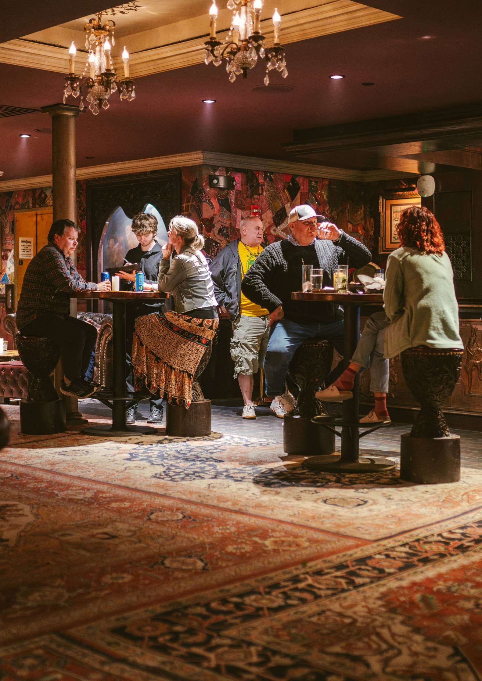 A couple of people sitting and standing around cocktail tables enjoying their drinks