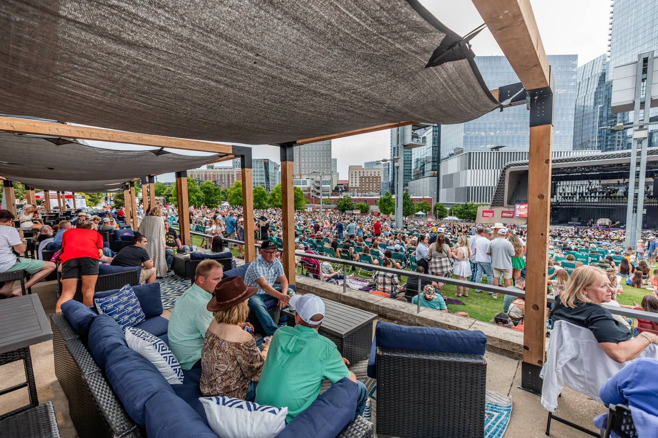 A group of fans enjoying the show from lawn cabanas overlooking people on the lawn. 