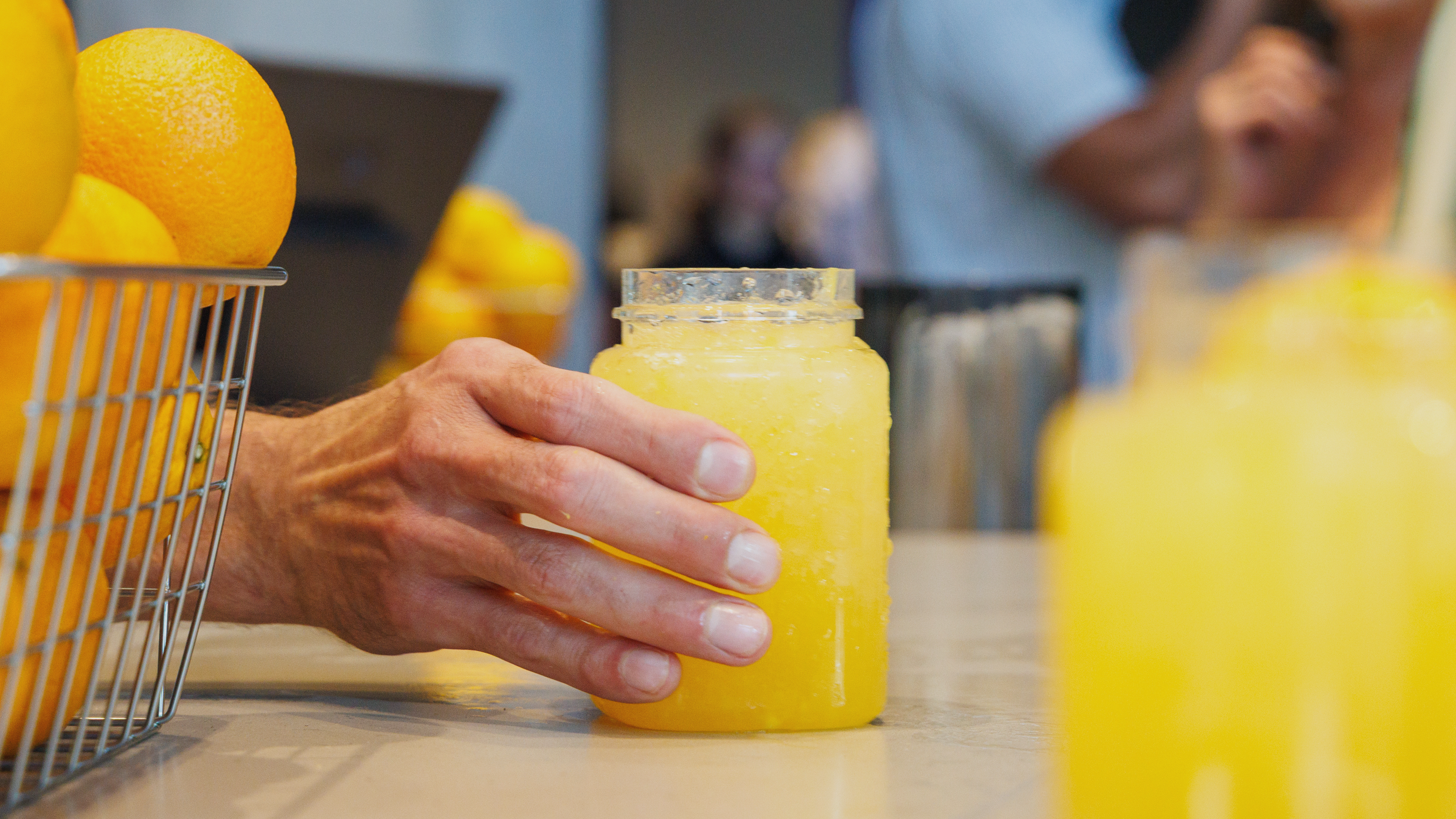 Photo of a servers hand presenting The Dome's Orange Crush Cocktail at the main bar. 