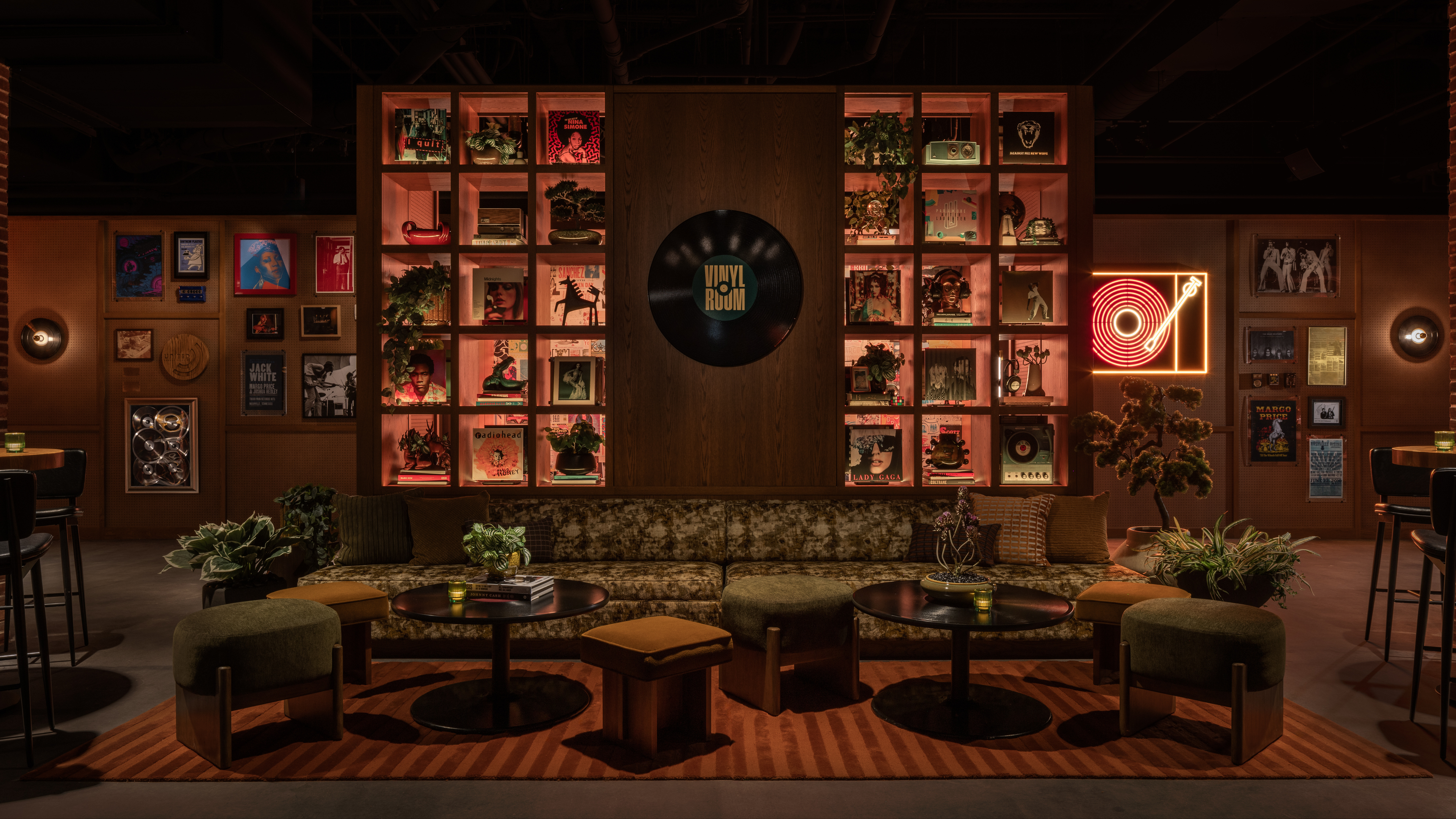 The Vinyl Room lounge at The Truth, with plush seating, record-inspired décor, illuminated display shelves, and a neon turntable sign. Photo credit: Evan Joseph