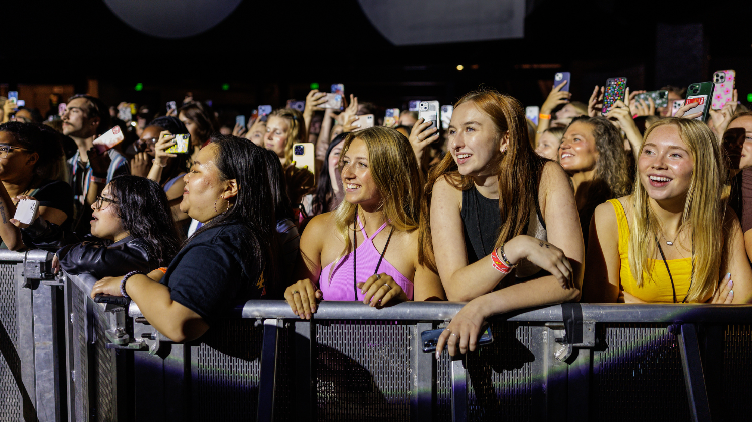 A group of people smiling at the barricade during a show