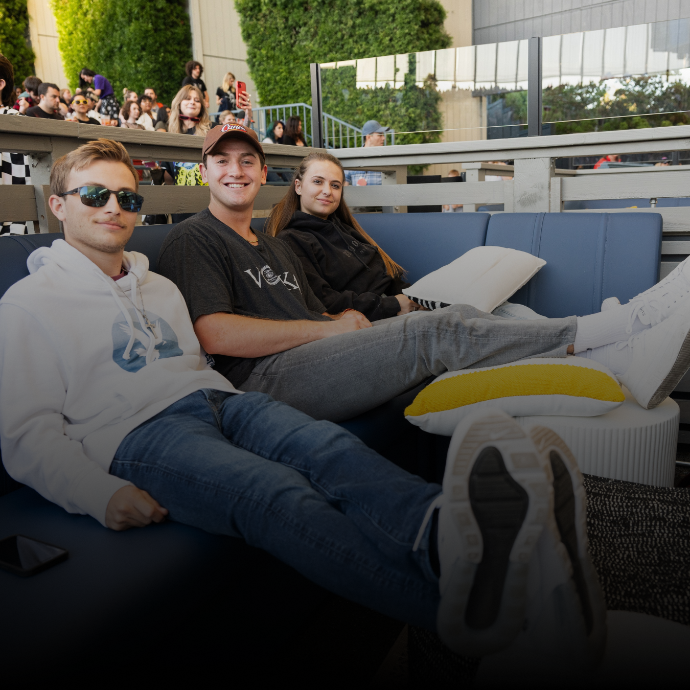 3 young people lounging on a couch with their feet up, smiling at the camera
