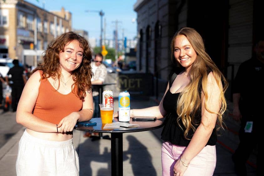 Two people smiling and facing the camera with drink on the table
