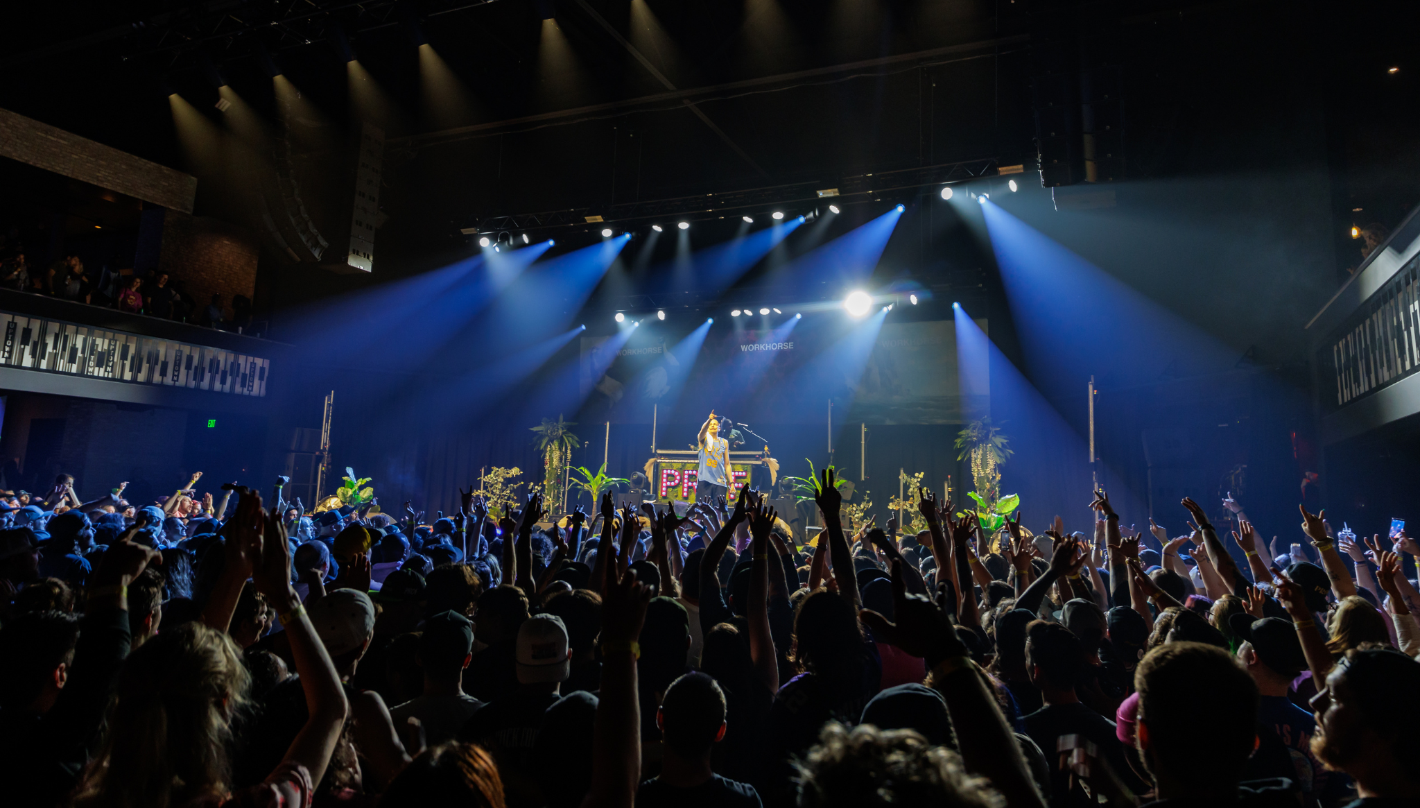 A view from behind of the crowd raising their hands