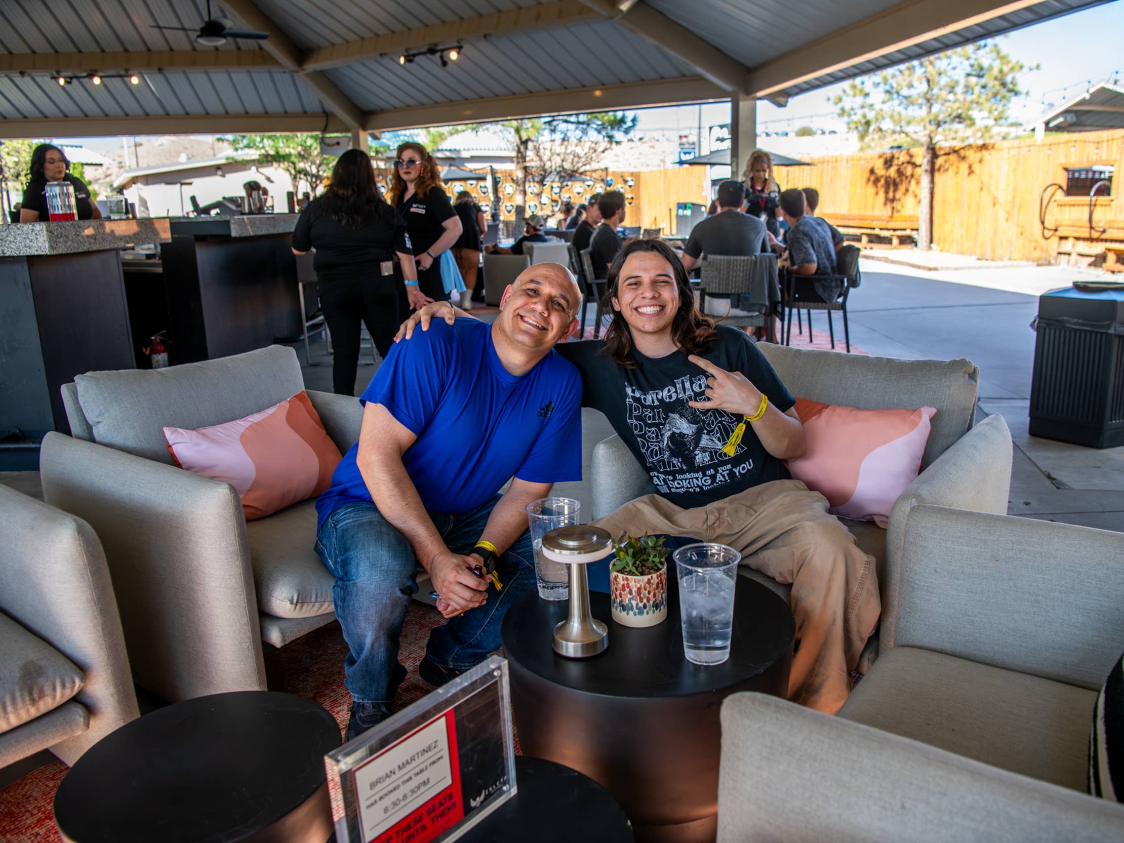Two men sitting in the VIP Club. Sitting in comfortable armchairs, smiling, with a table with drinks in front of them.