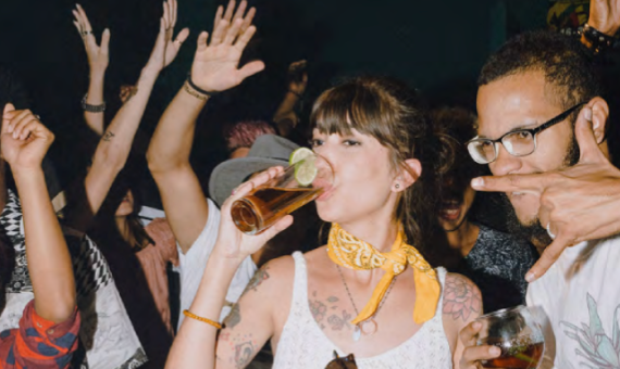 A close up of a crowd holding or drinking from a glass cup. 