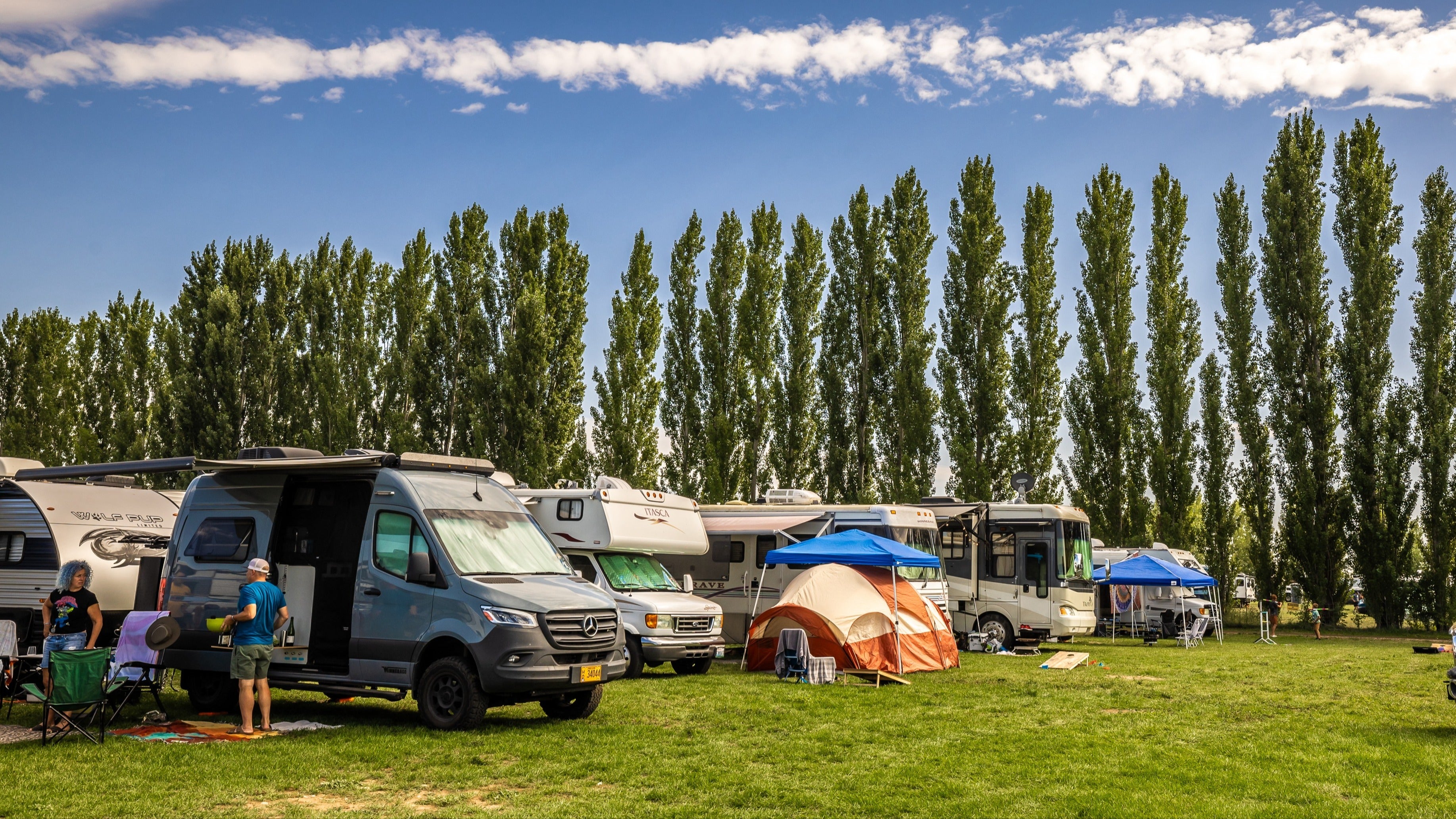 Vans and RV parked and set up to camp on a lawn