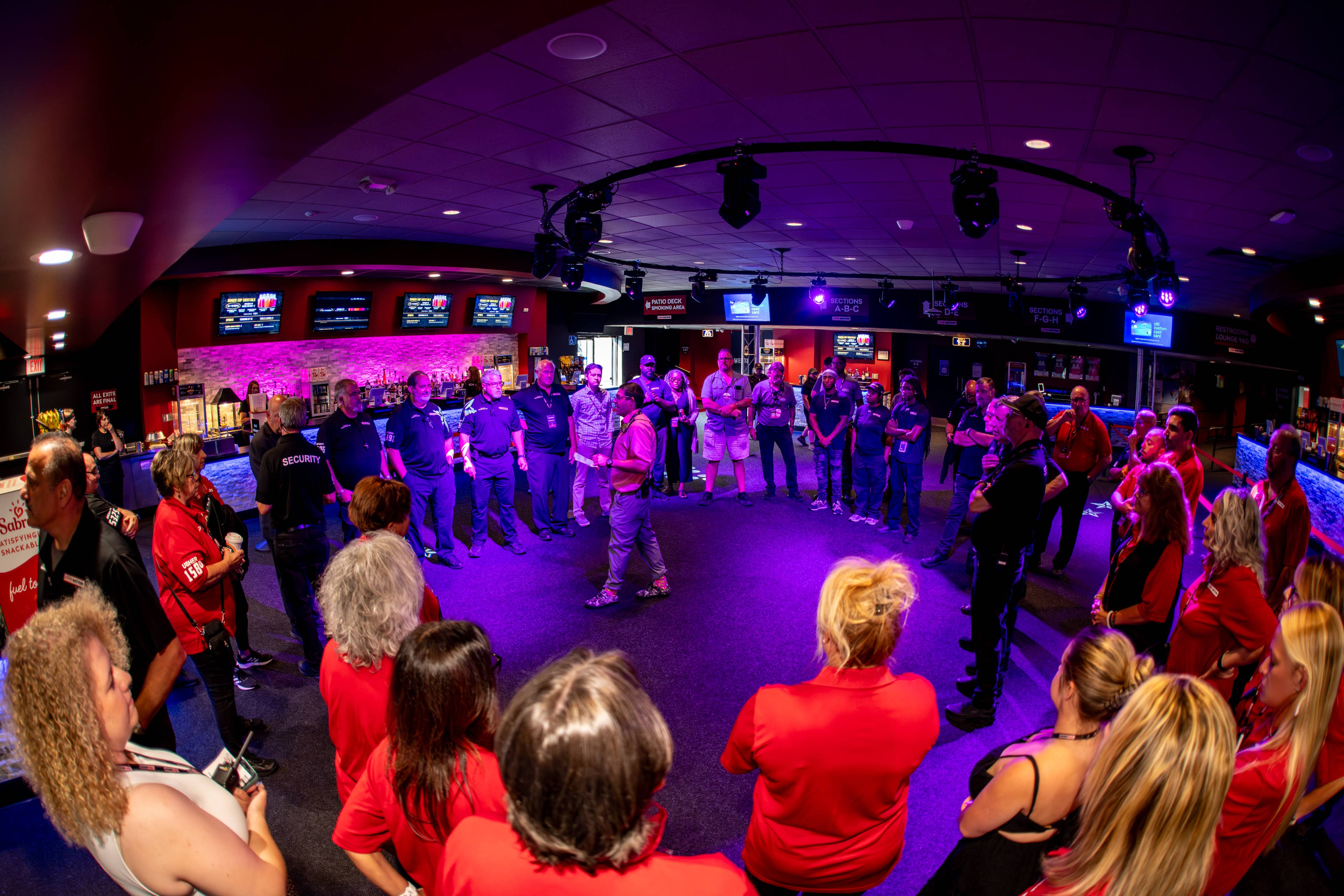 Staff members standing in a circle in the Lobby during a staff meeting