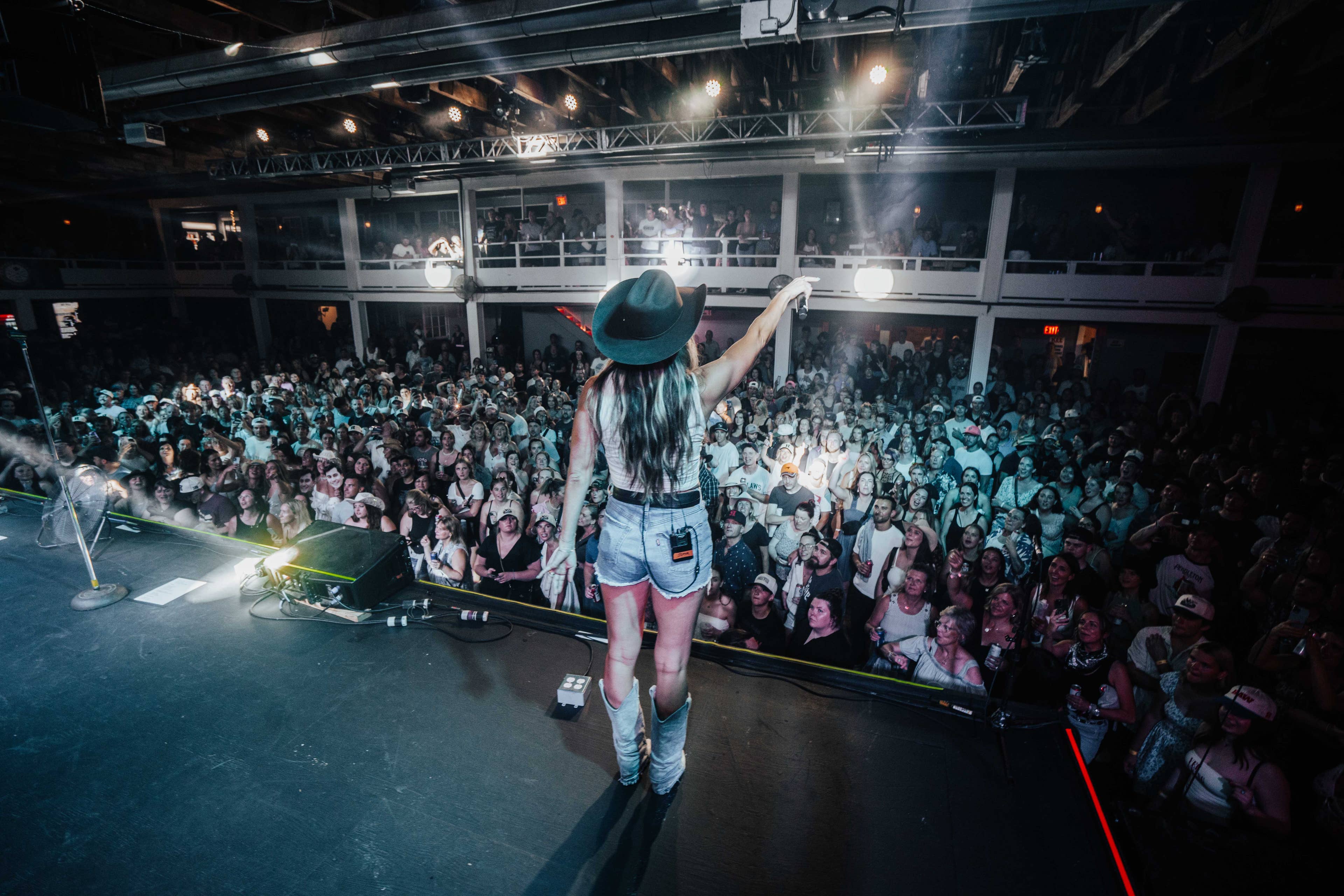 view of the crowd at  the kee to bala taken on the stage with the artist performing's back profile