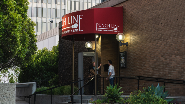 Three people standing and talking in front of Punch Line San Francisco's entrance.