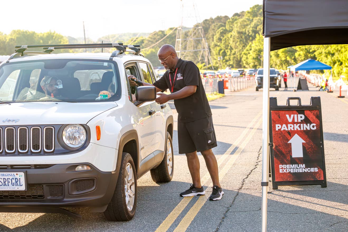 A male worker at PNC Music Pavilion helping fans arrive at VIP Parking.
