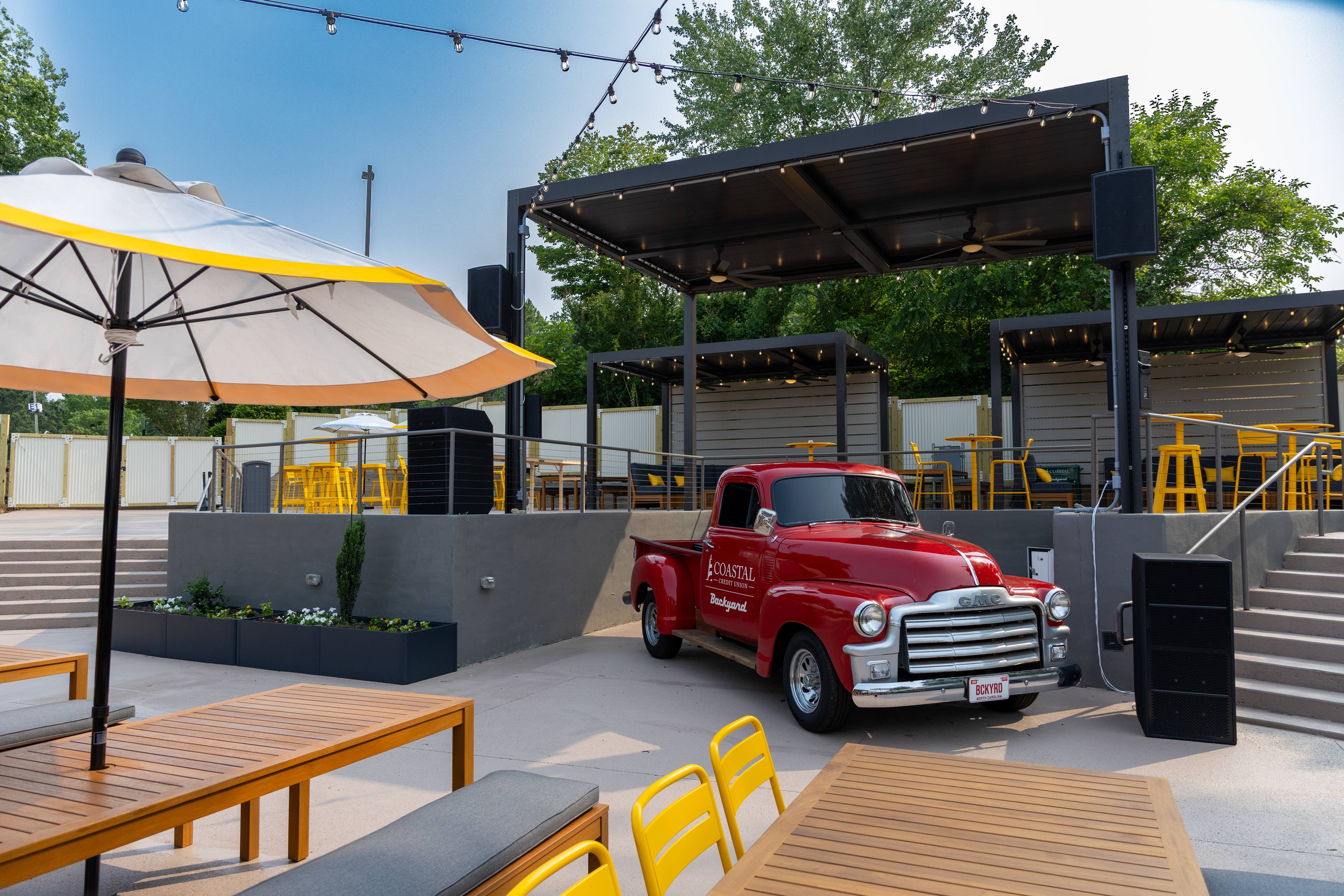A picture of a red truck and yellow tables and chairs.