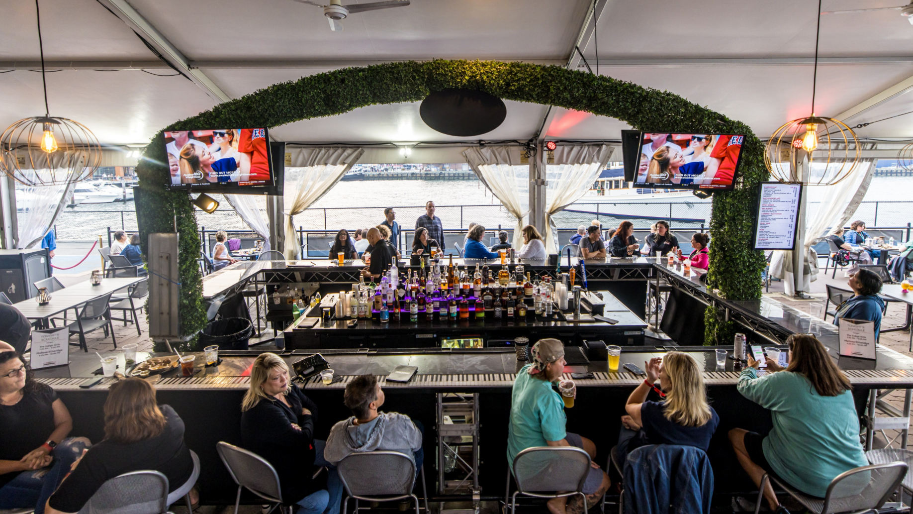 Fans sitting around a bar with views of the Harbor in the background. Television screens hang overhead.