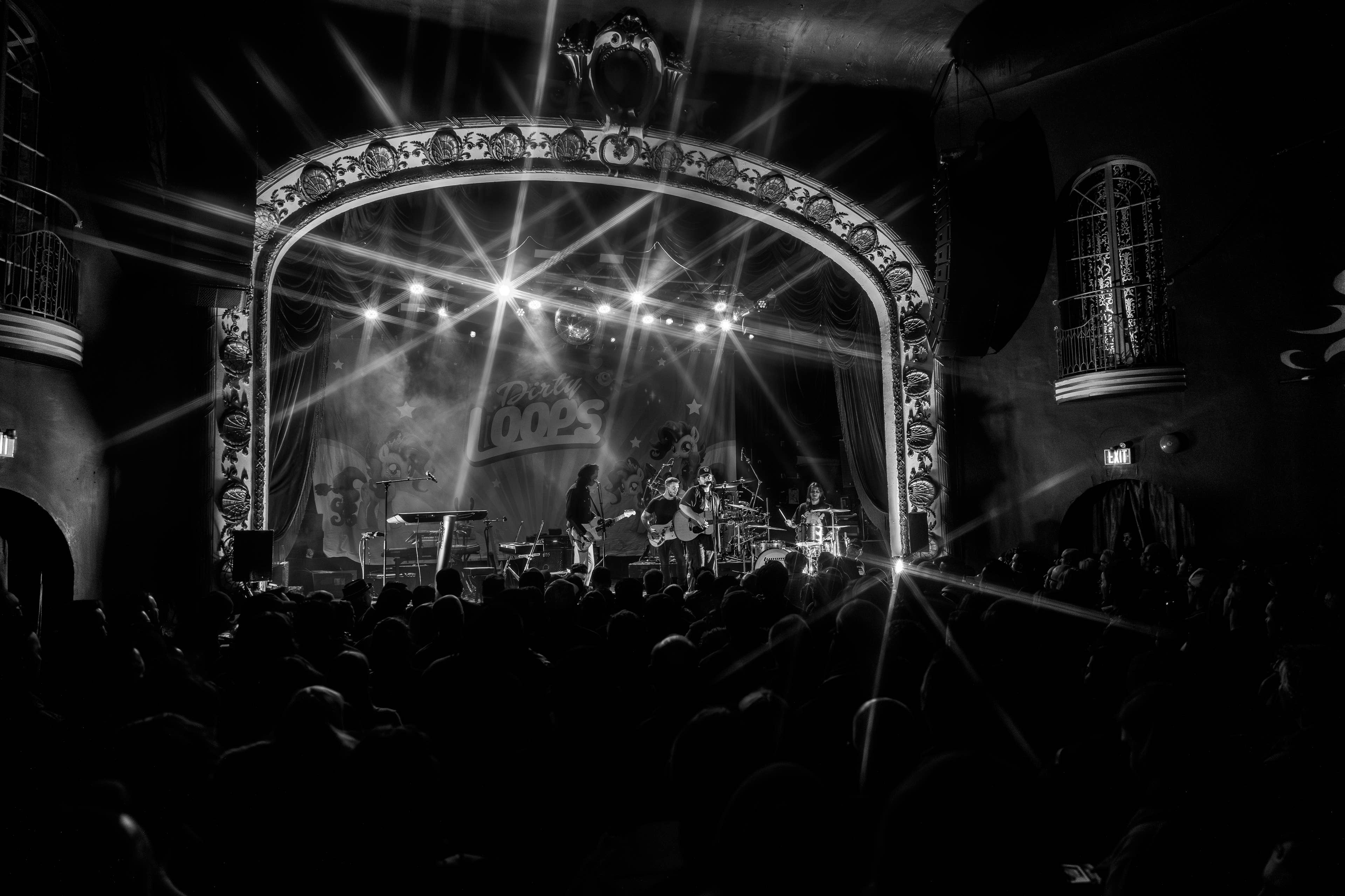 A view of a crowd and a band playing on the stage in black and white