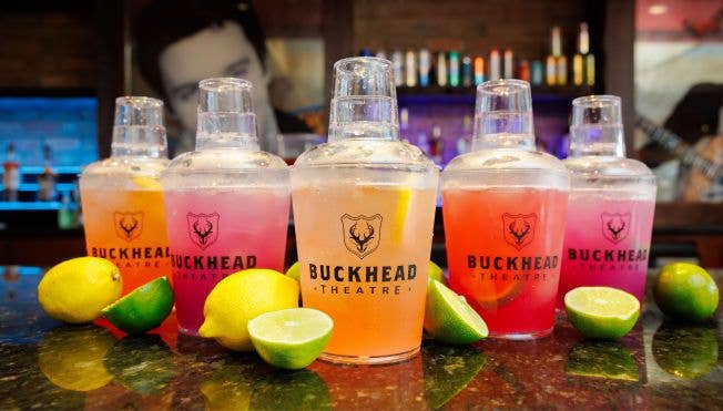 Five cocktails in cocktail shaker shaped cups with lemons and limes around them