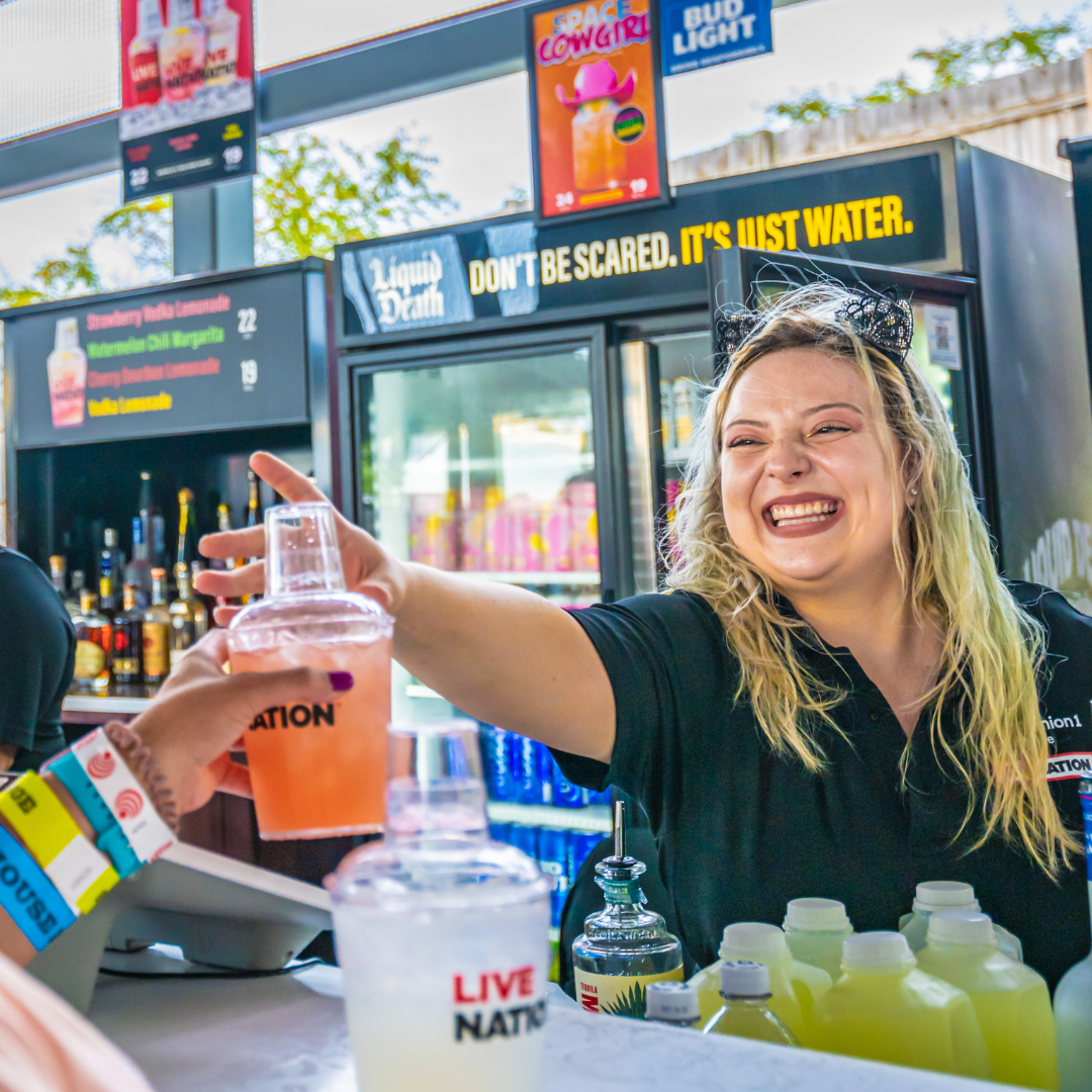 A venue bartender serving a fan a cocktail.