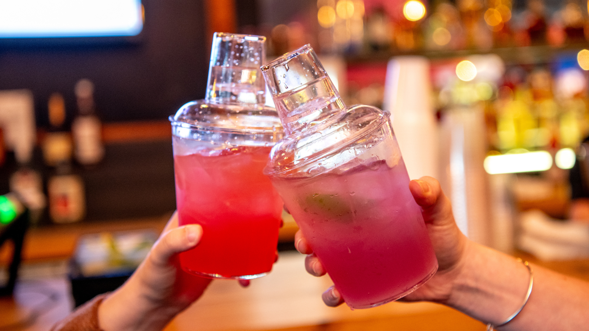 Two shaker cup cocktails, being clinked together