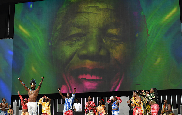 Vibrant concert scene with colorful stage lighting effects in green, blue, and purple illuminating performers