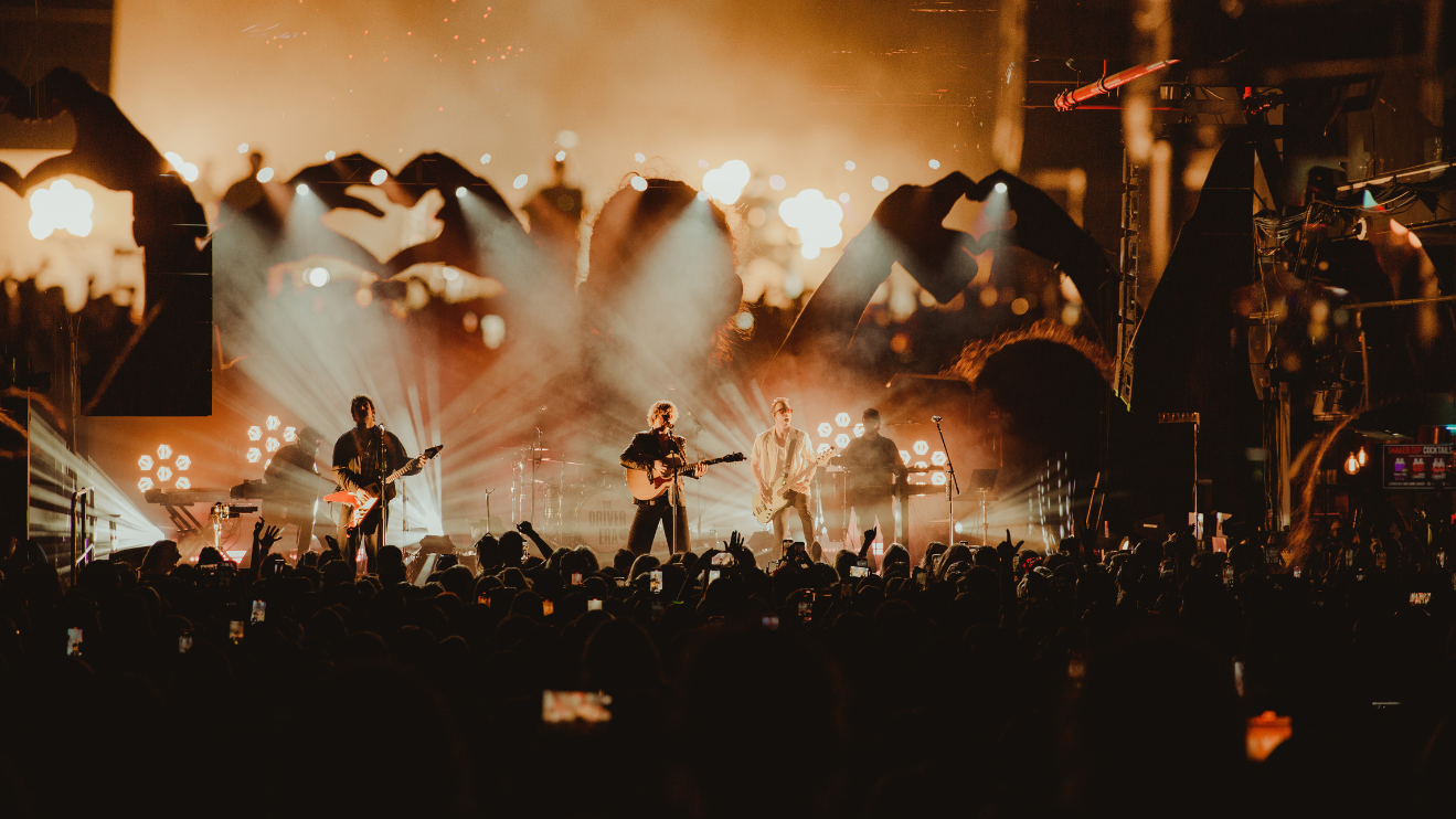 A photo of The Driver Era performing at The Fillmore Charlotte with an overlay of fans hands in a heart shape.