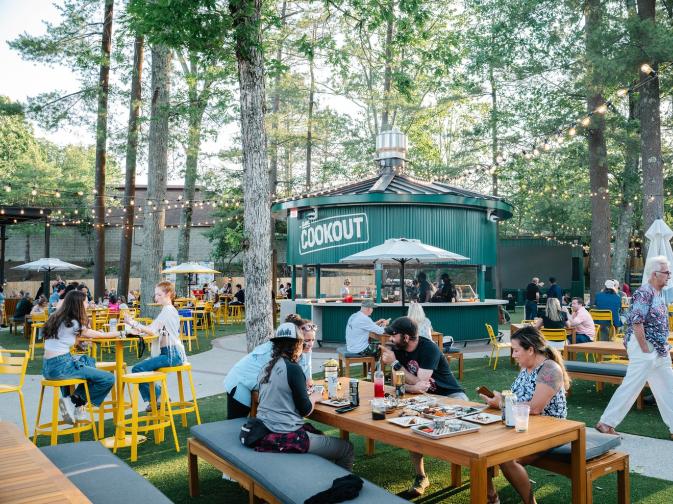 An outdoor space with people enjoying food with a concession area called "The Cookout"