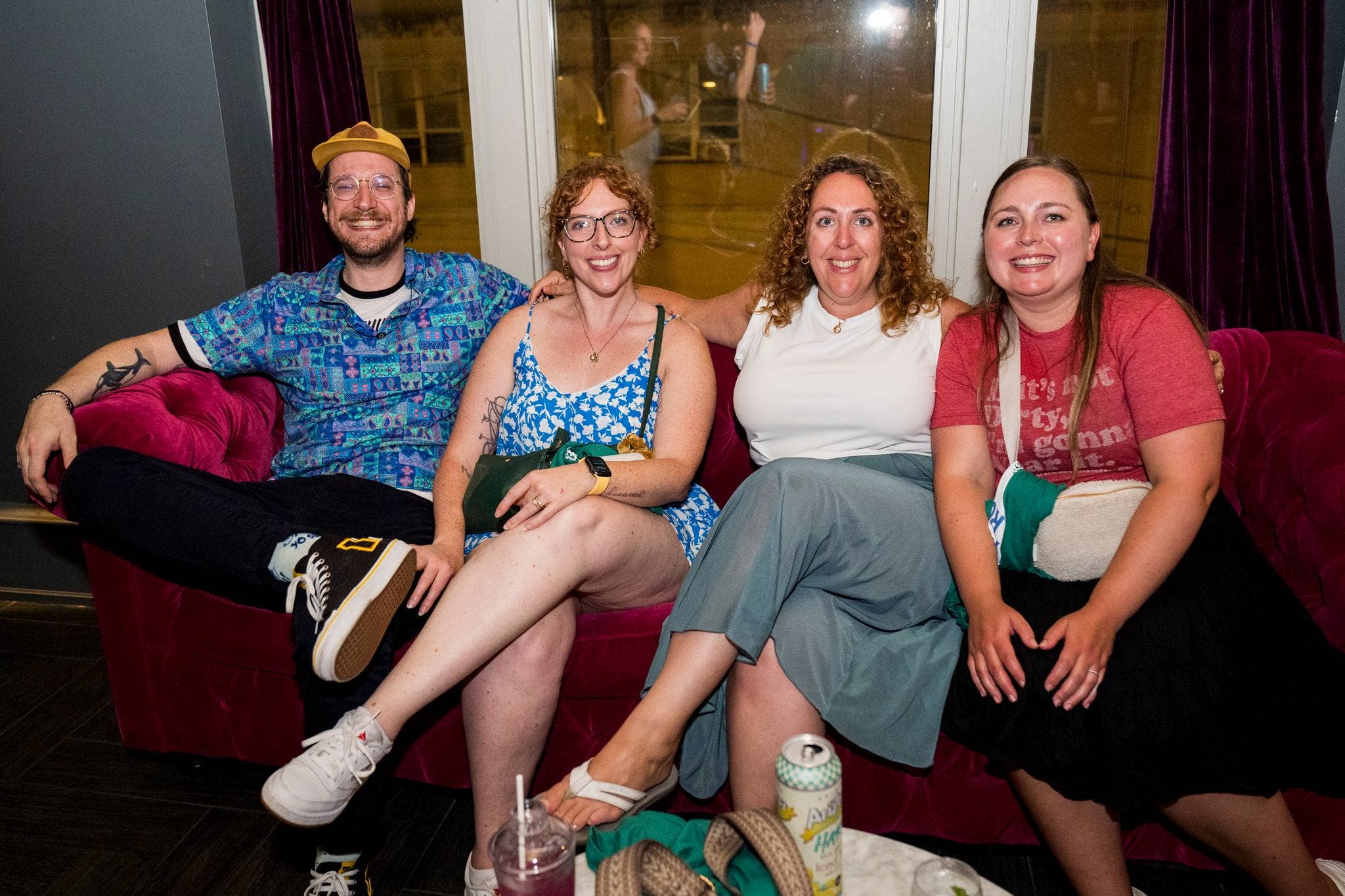 four people sitting on a couch smiling at the camera
