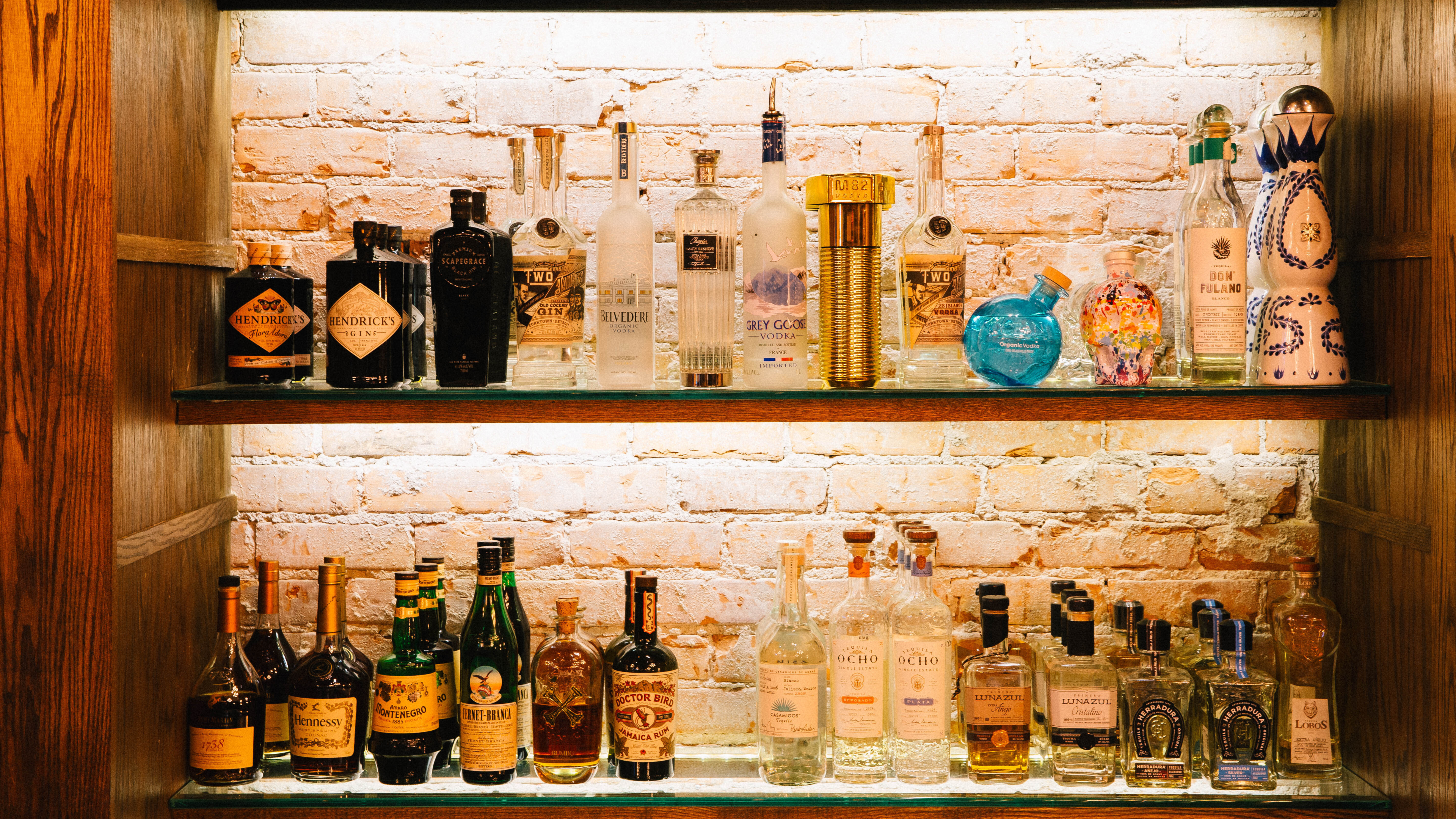 A view of a bar with two shelves and various liquors. 