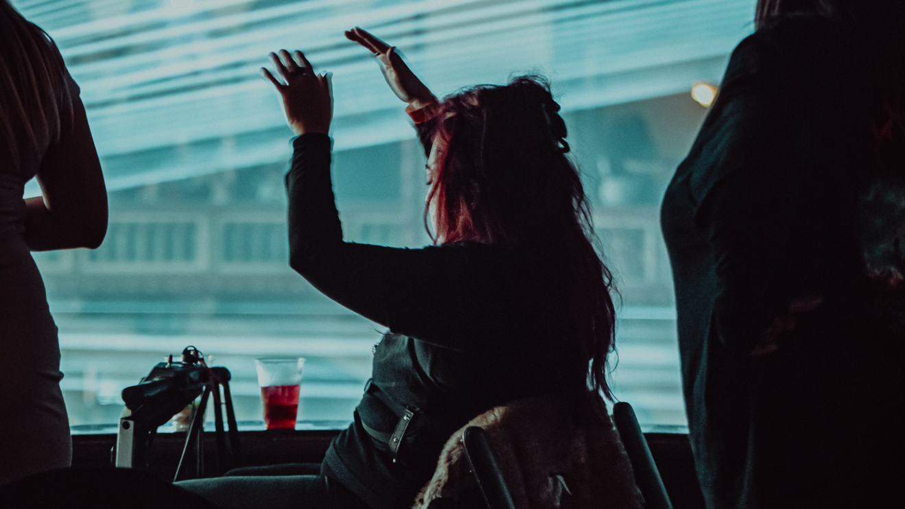 A fan raises their hands in the air while watching a concert.
