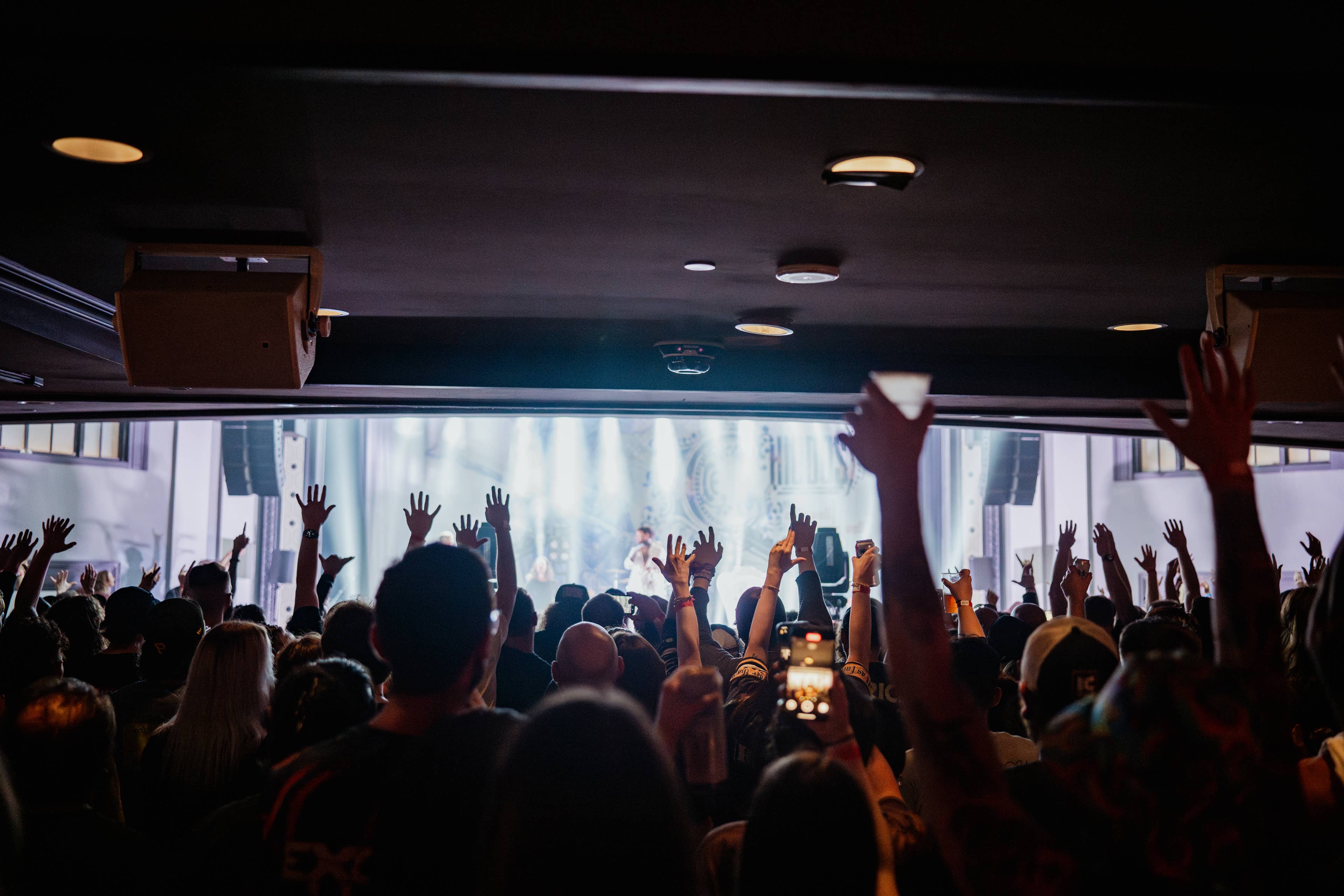 Crowd cheering as band performs on stage. 