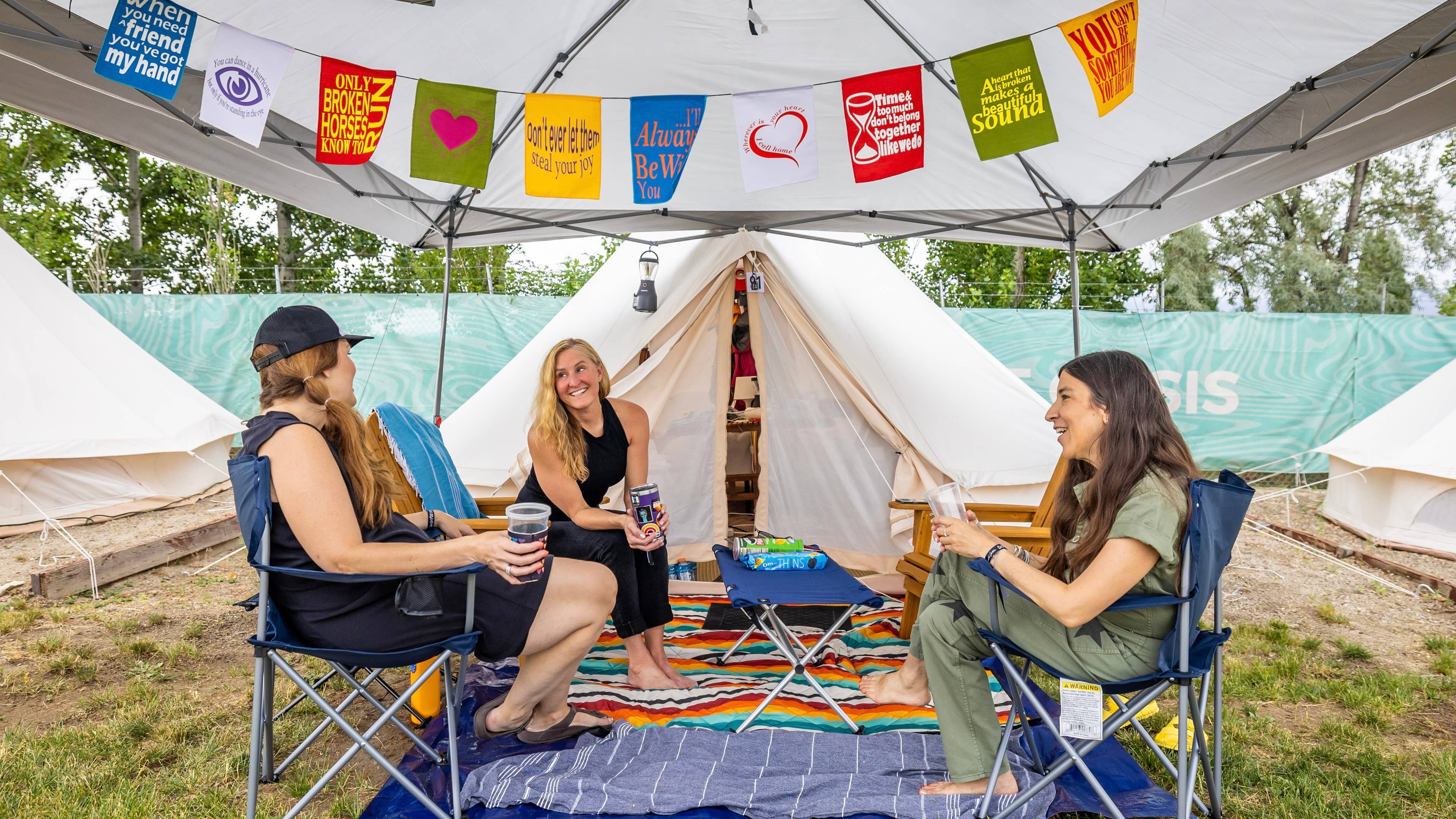 Friends sitting in glamping campground with drinks in their hand