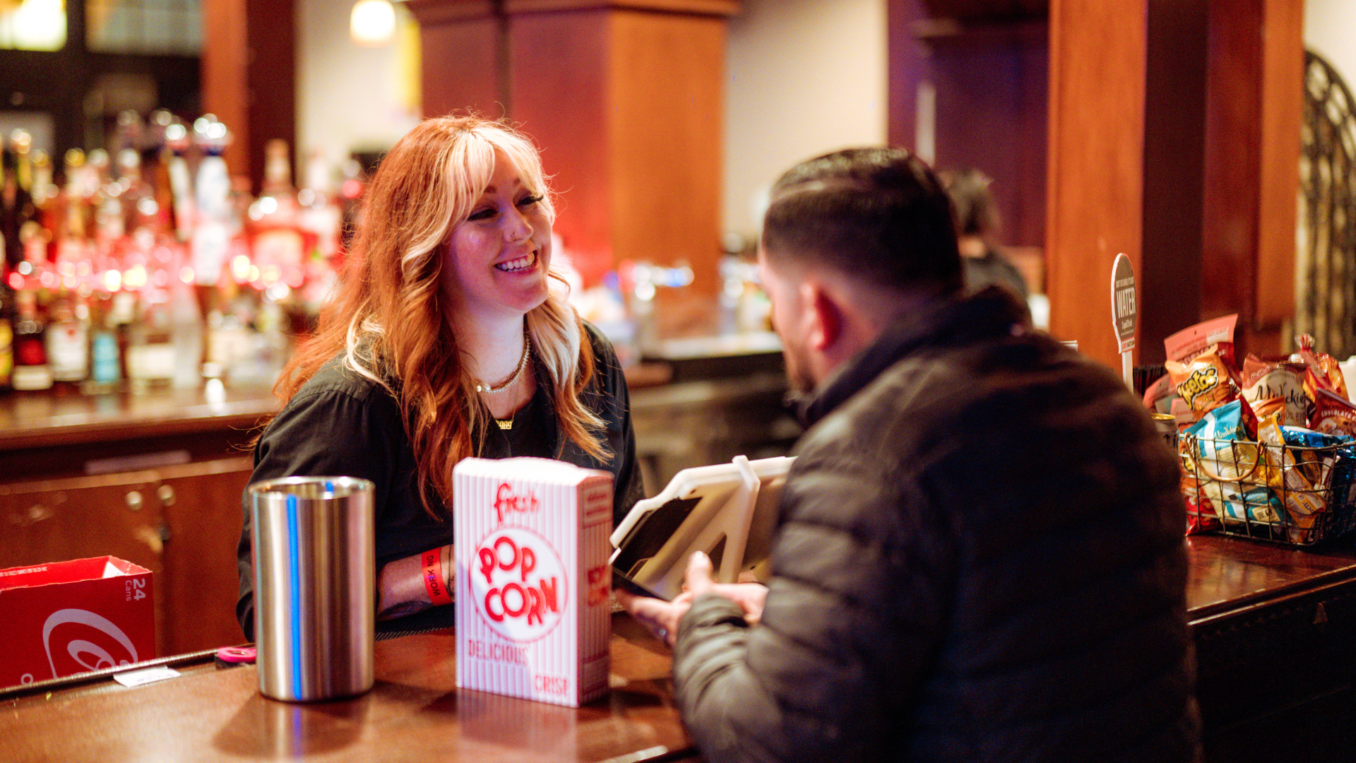 a picture of one of our employees serving a customer popcorn with a smile on her face