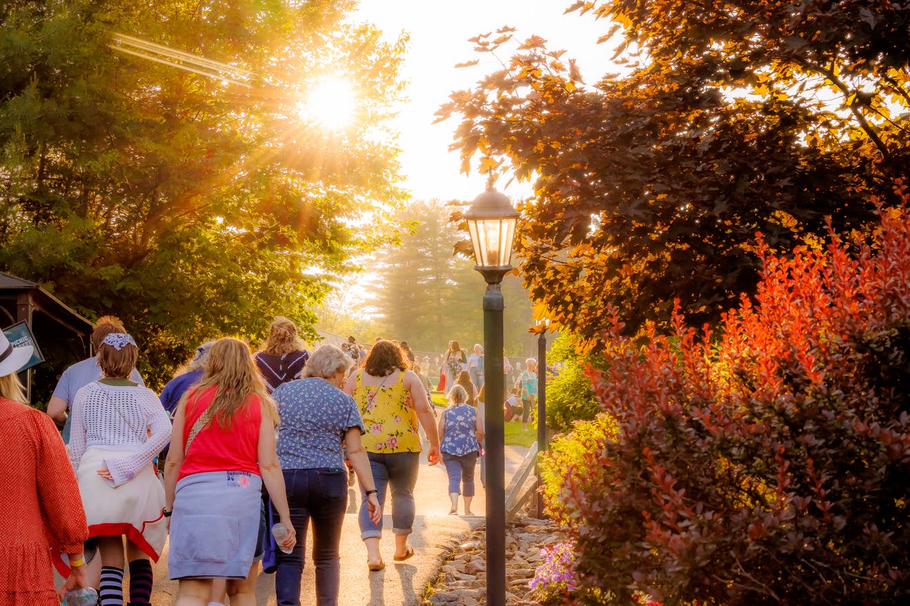 Fans walking through a sunny path with foliage 