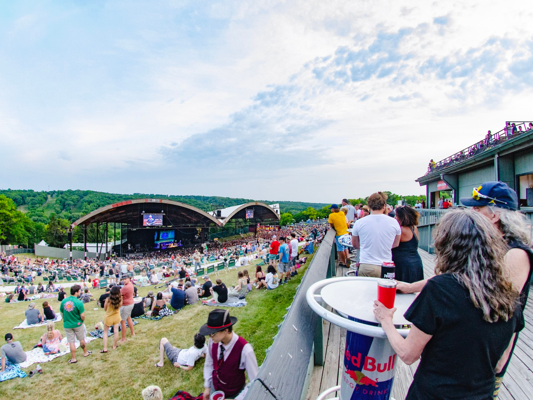 People standing on a deck overlooking the lawn and the stage at Alpine Valley Music Theatre.