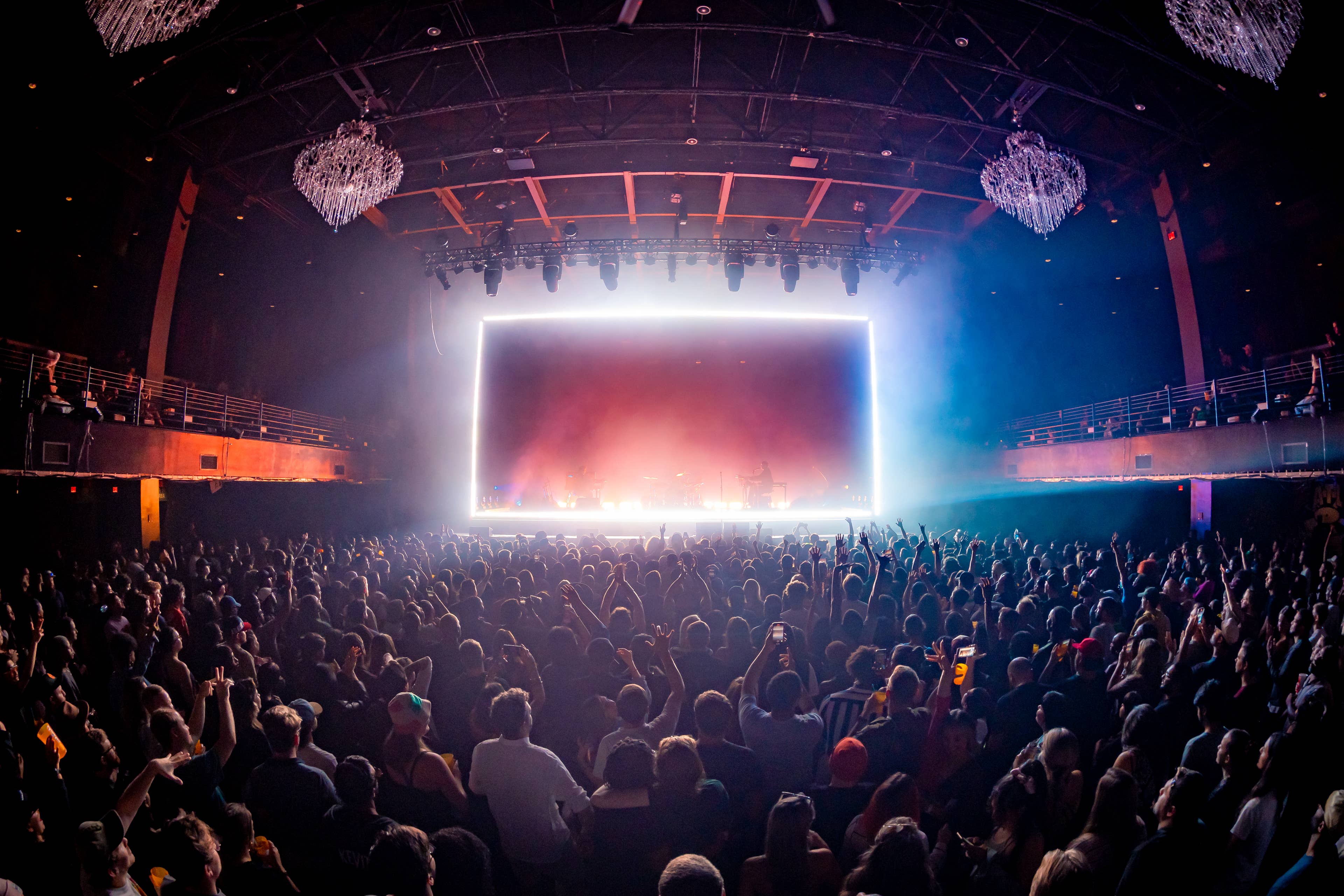 A crowd of people cheering during a concert.