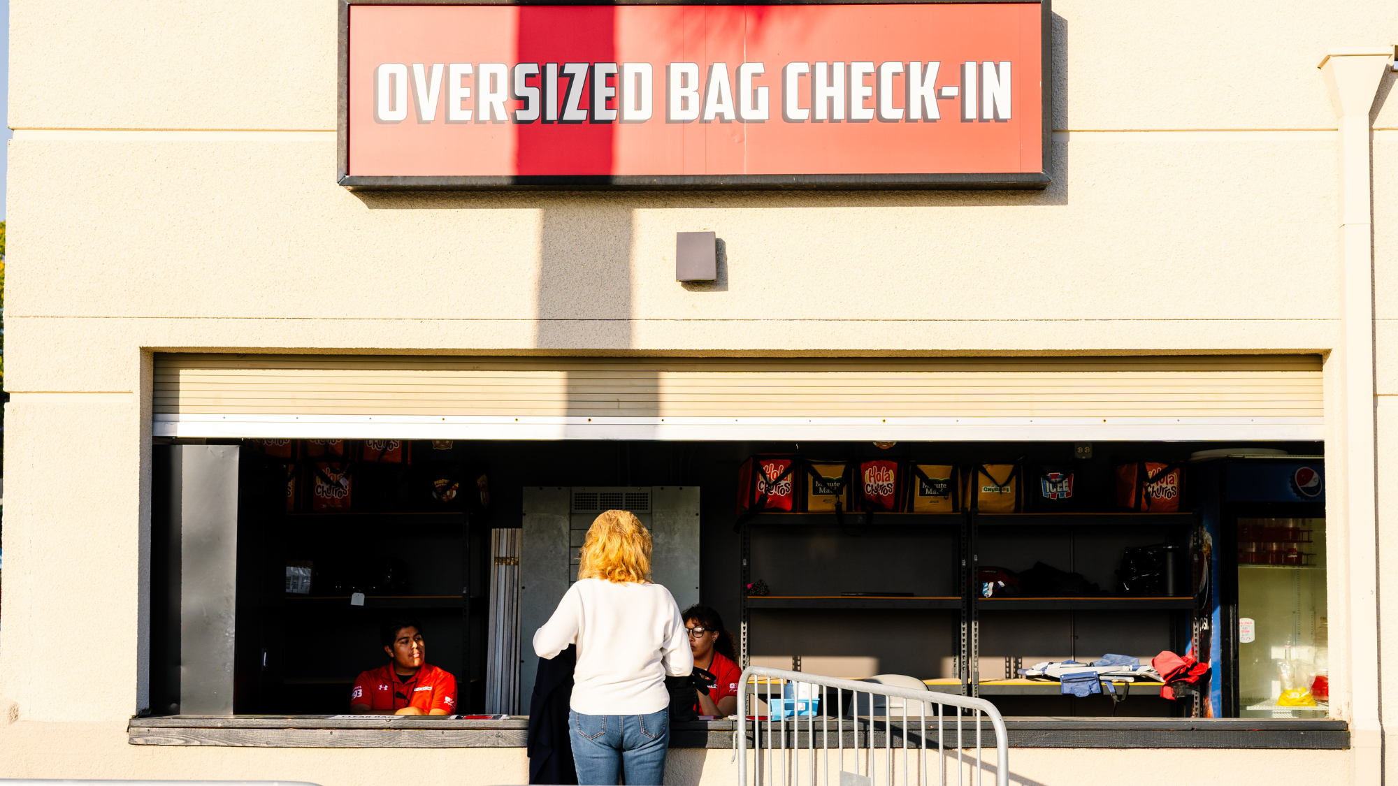 A woman speaks to an employee at the oversized bag check-in stand.