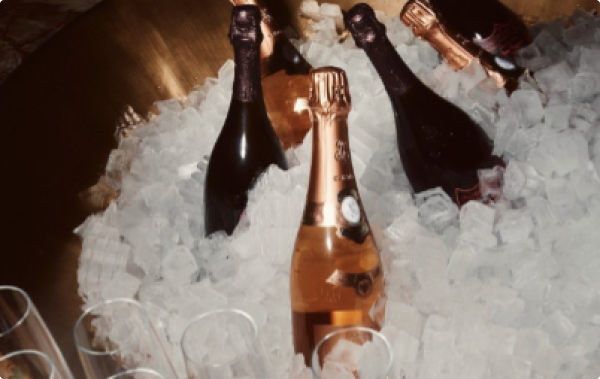 A bucket of three champagne bottles on ice
