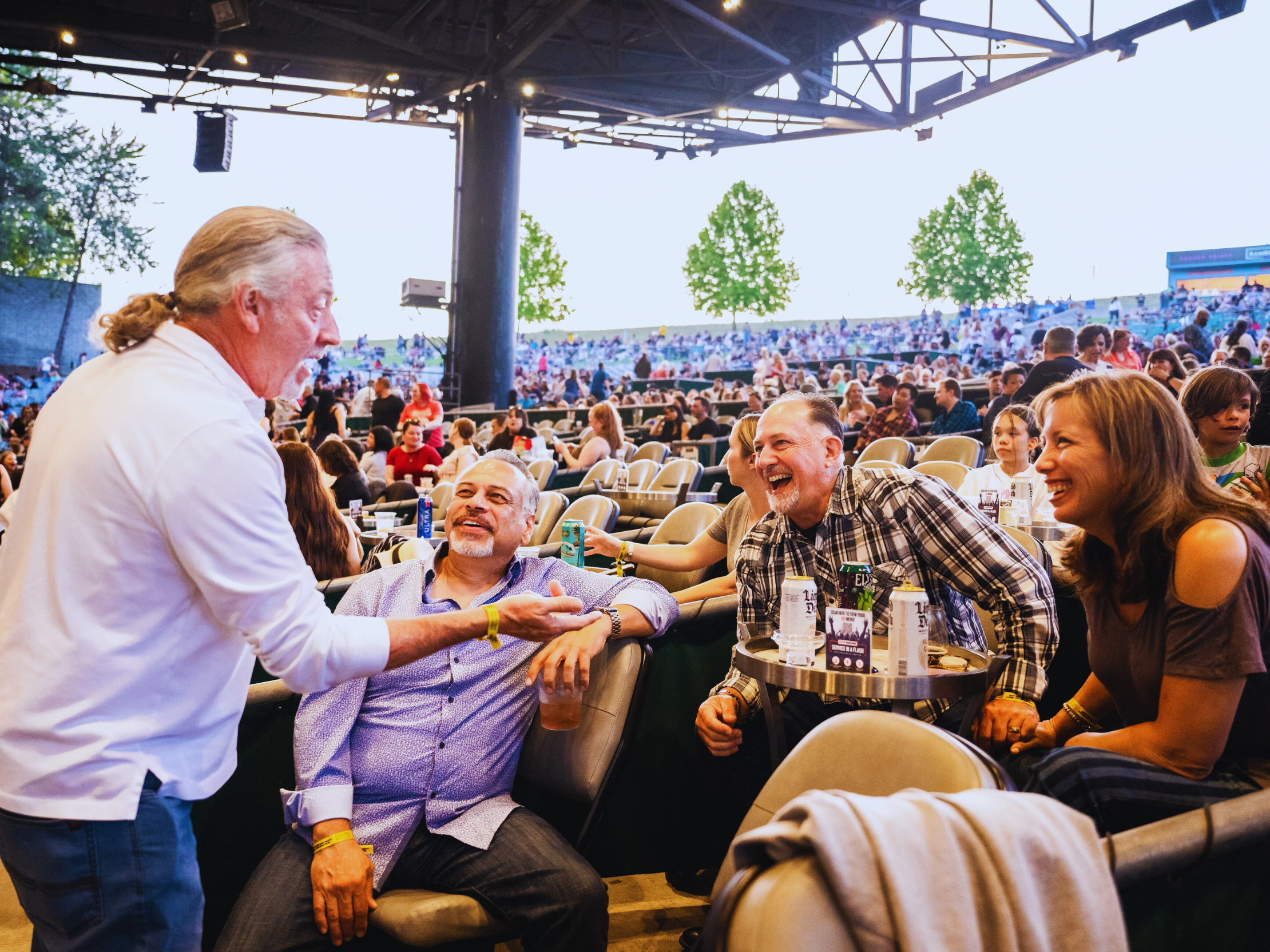 Fans sitting in premium section with drinks, talking and laughing with each other