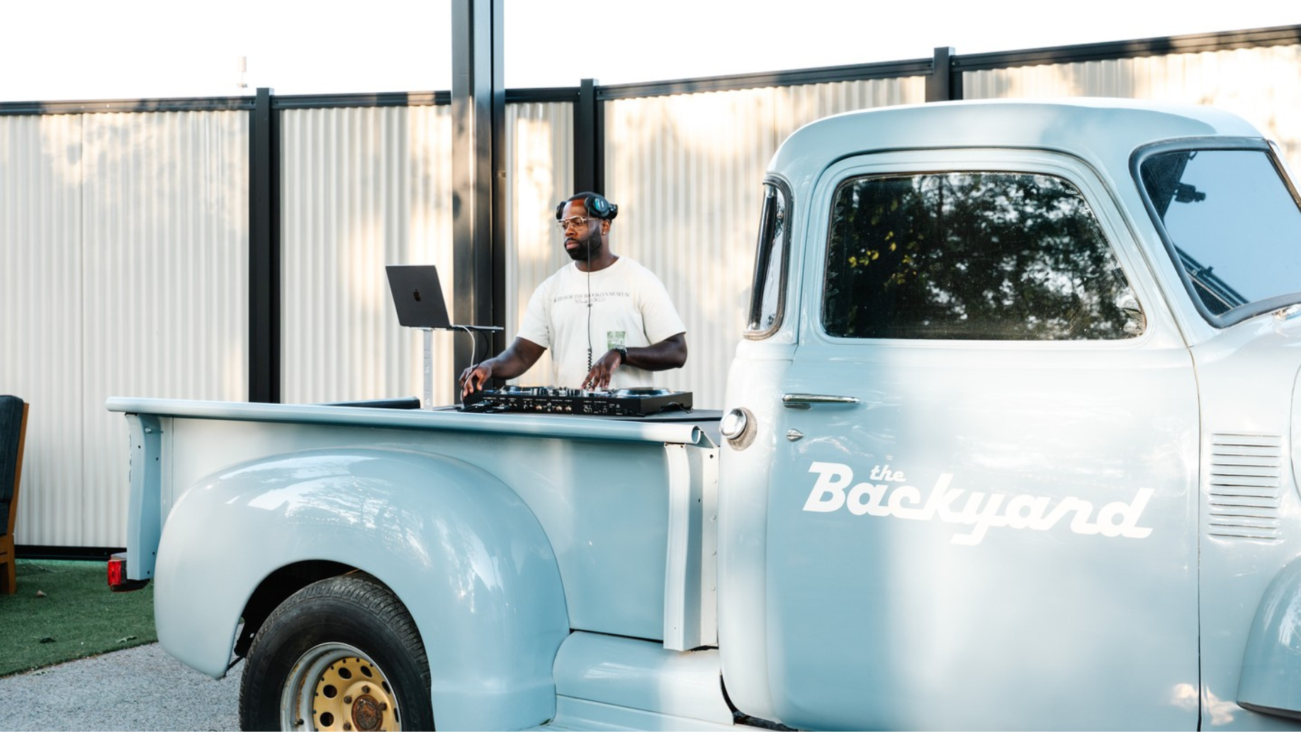 A baby blue truck with the BackYard signage and a DJ playing music
