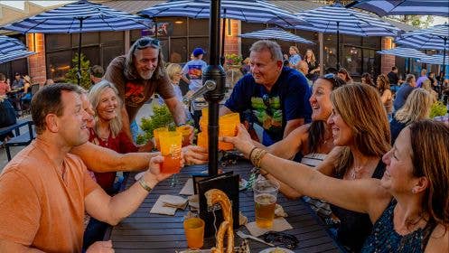 Group of guests at a picnic table smiling and holding drinks