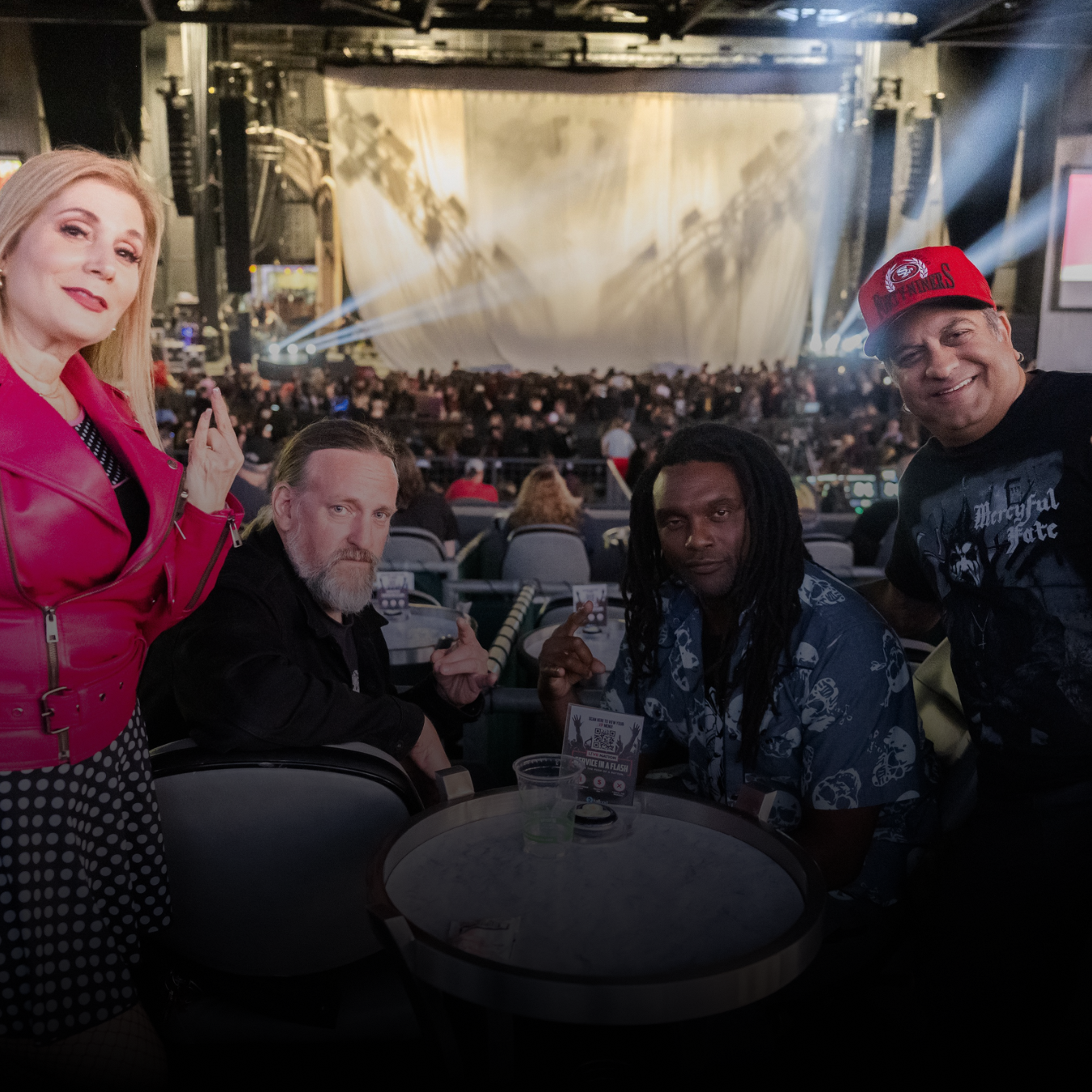 Group of four people standing and sitting with the stage in the background