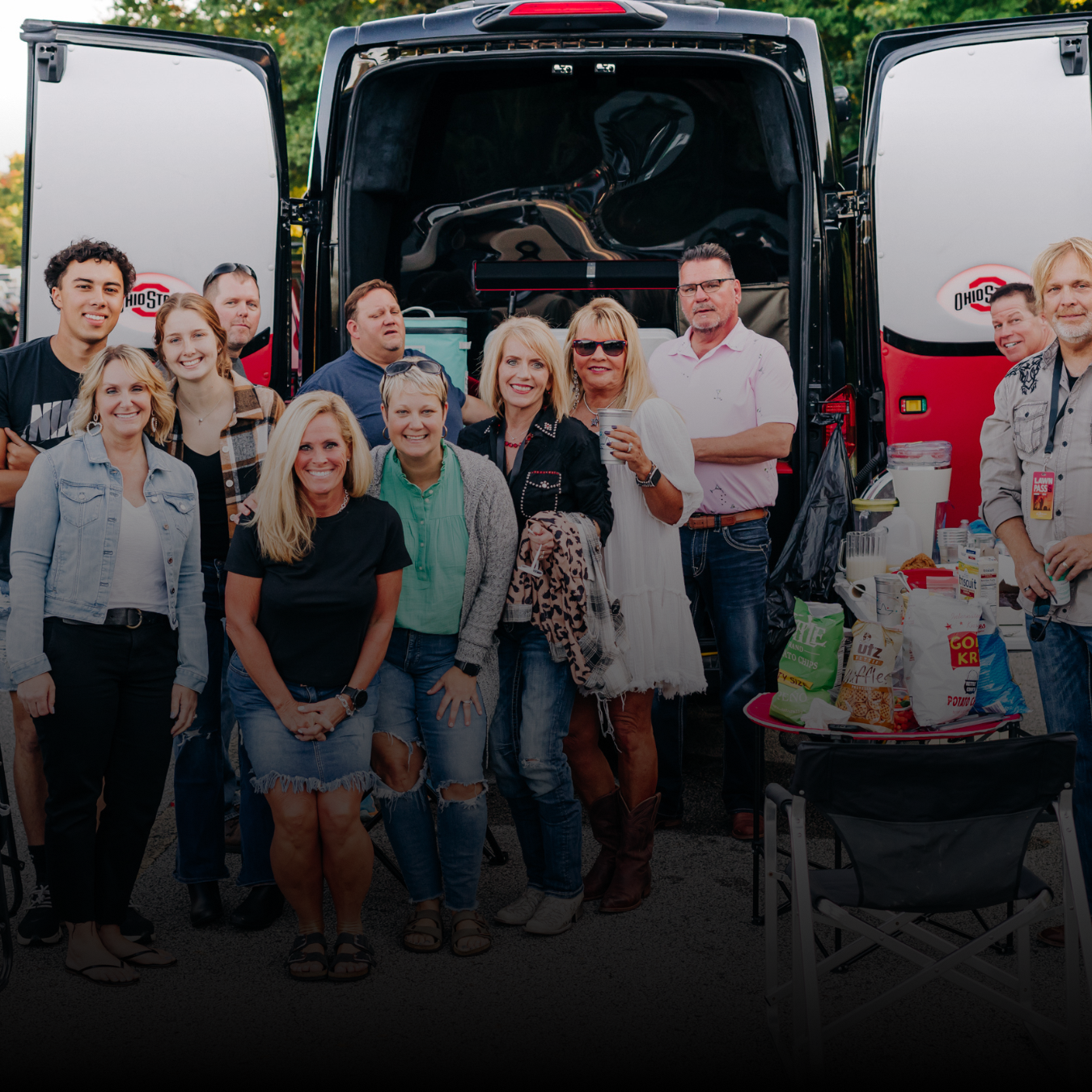 Group of fans posing for a photo beside a van in the parking lots.