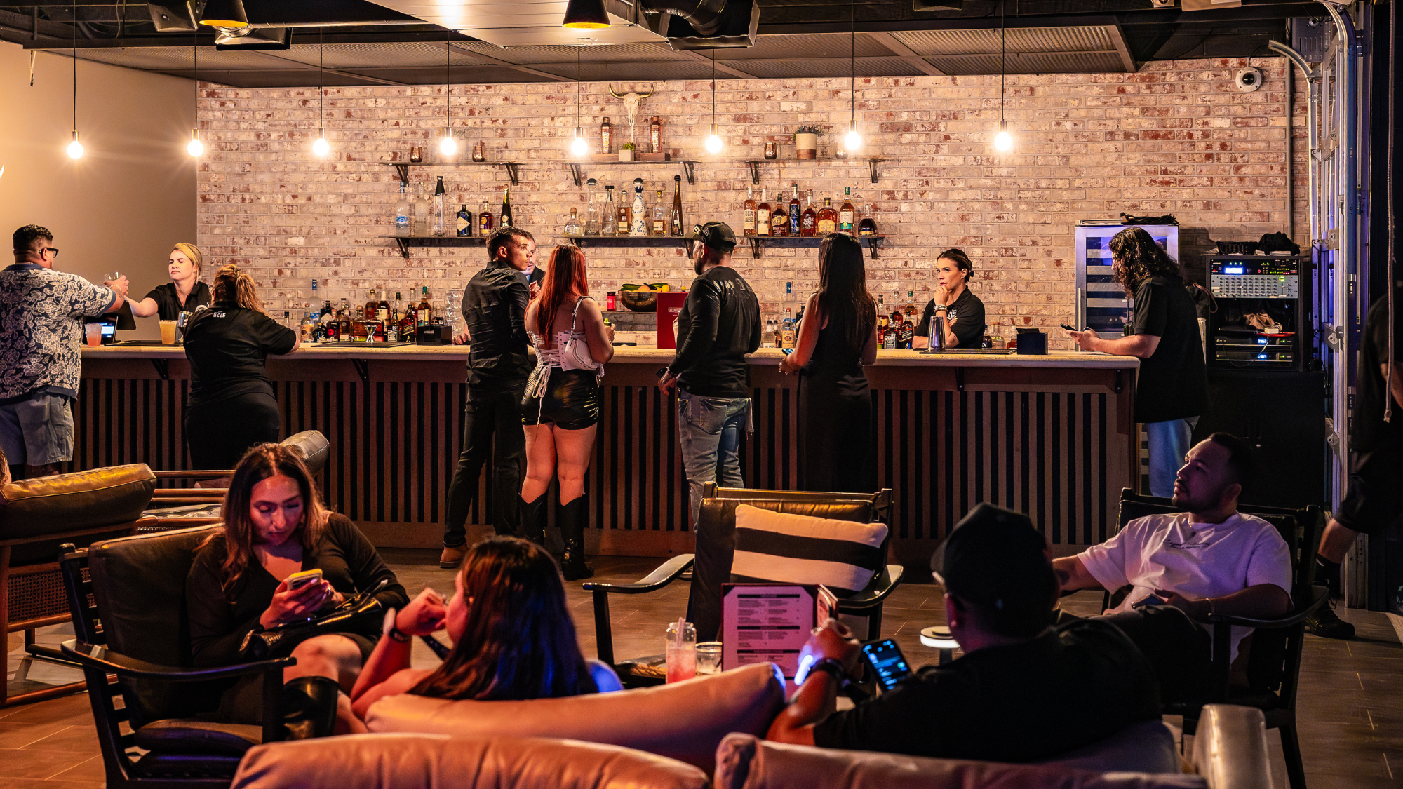 A group of fans order drinks at the bar and another group of people relaxes in chairs.
