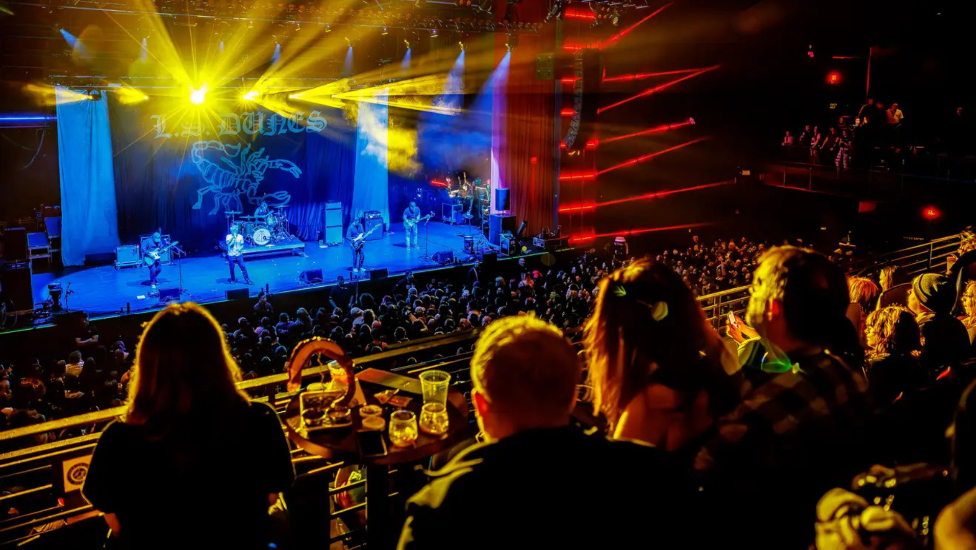 Fans gathered in a booth while watching a concert live and eating and drinking.