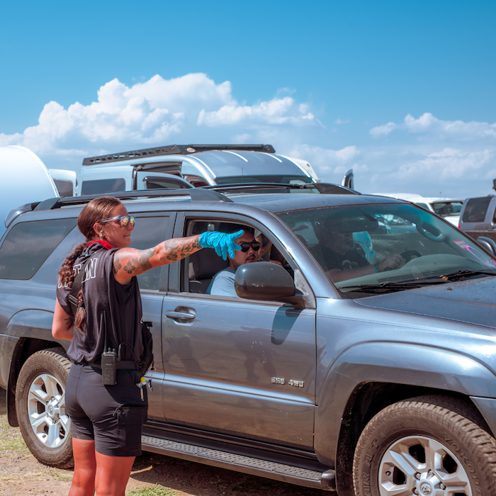 Guests in a car pulling up to the venue and an employee showing them where to park