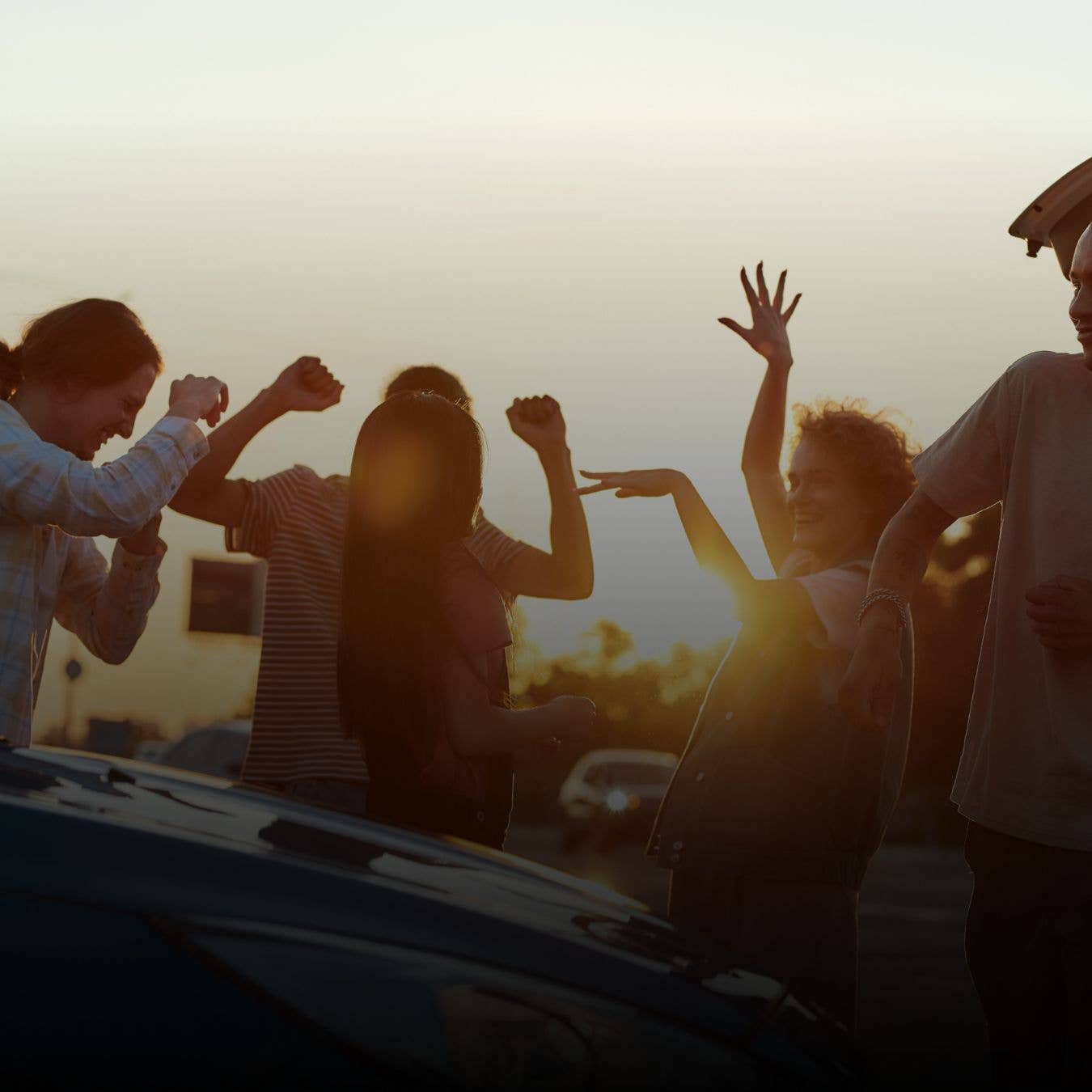 Fans dancing by a car in the venue parking lot