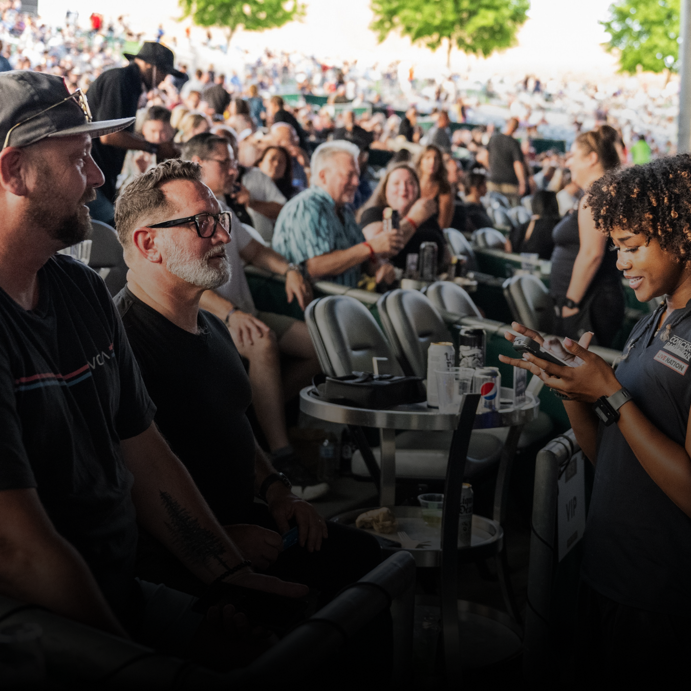 Employee taking the order of two fans sitting in their seats while the show is happening