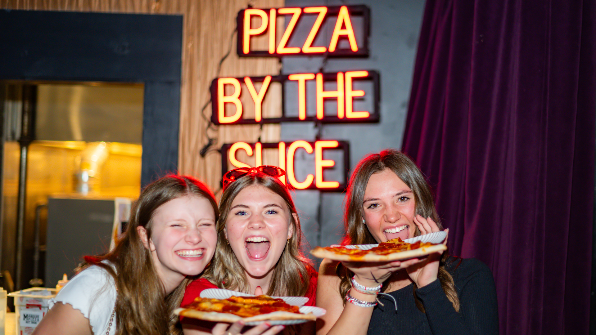 Three girls eating pizza at a show at Summit.